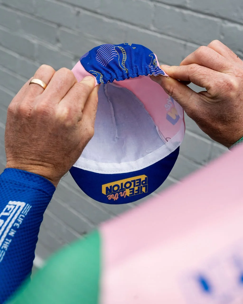 4. Hold the cap with both hands, placing your thumbs and pointer fingers on either side of the elastic at the rear.