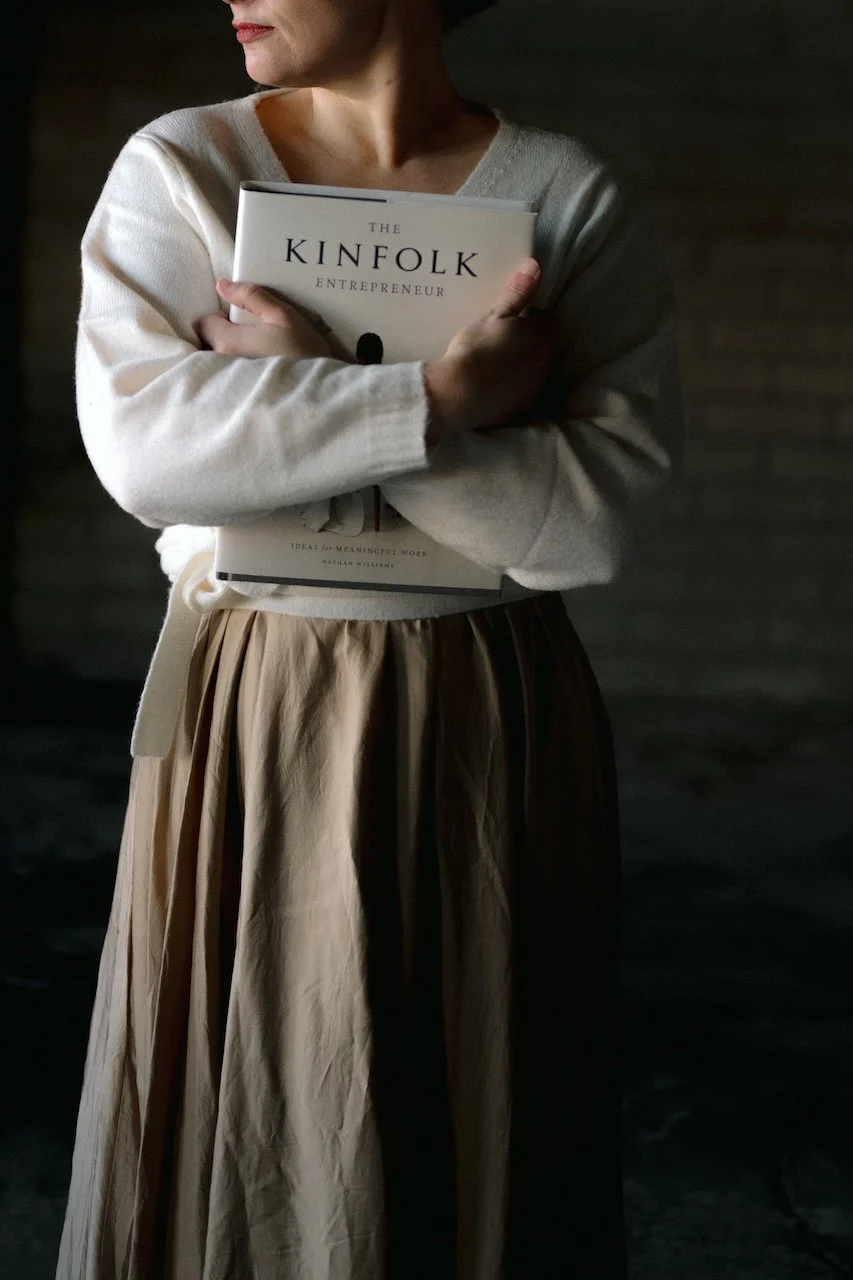 Nainen, joka pitää kirjaa titled "The Kinfolk Entrepreneur".