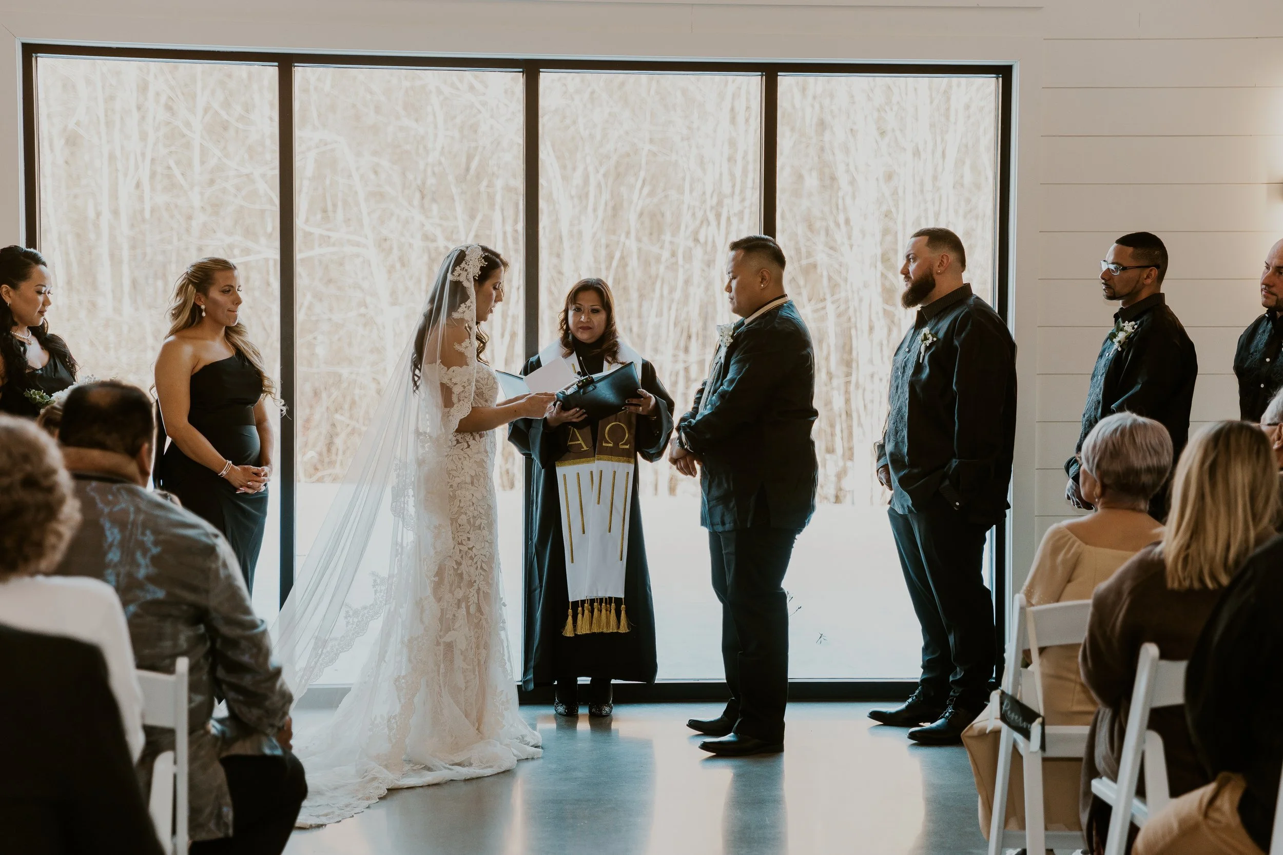 Couple against back windows during ceremony.