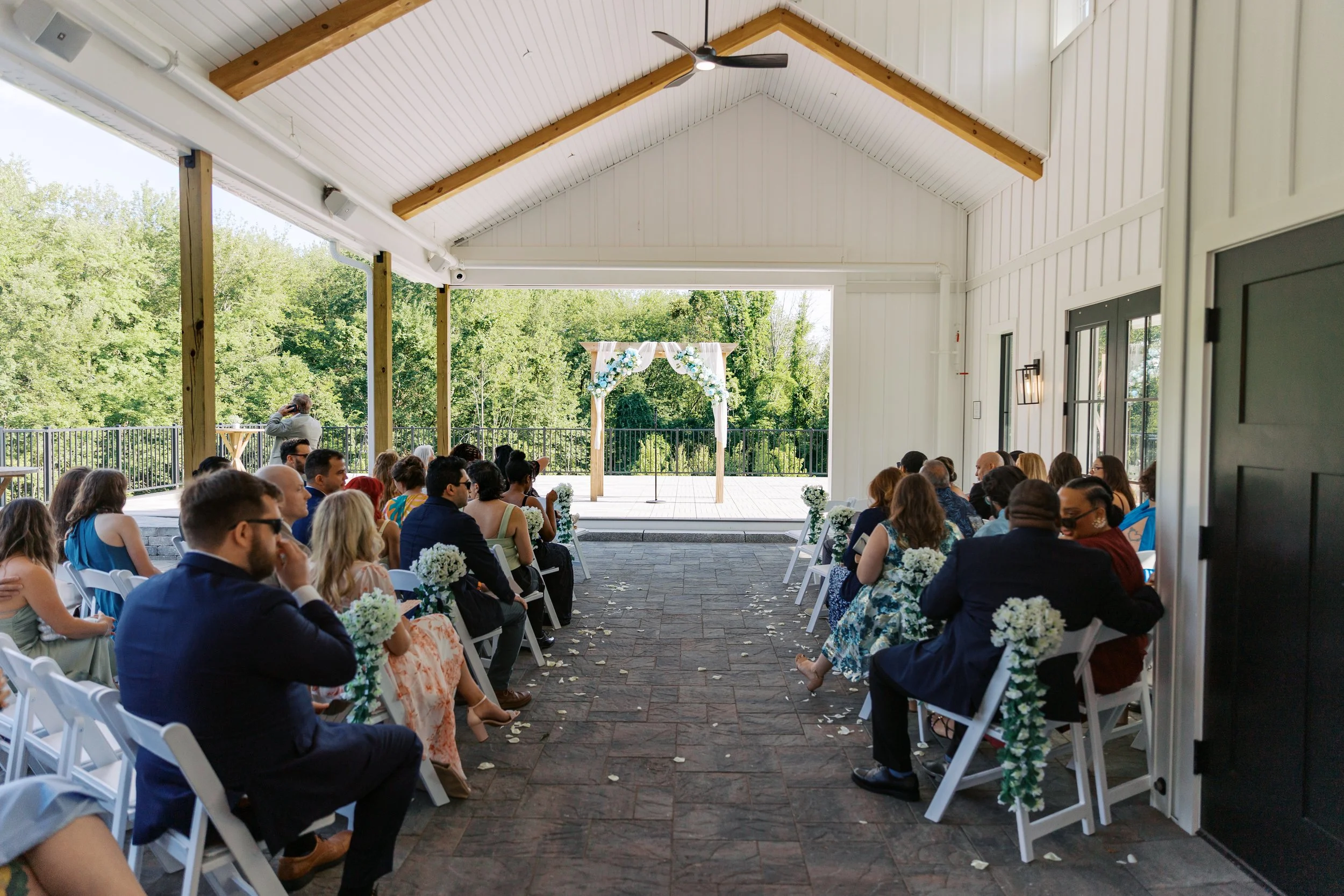 View of wedding ceremony located under the Covered Breezeway from behind guest seating. 