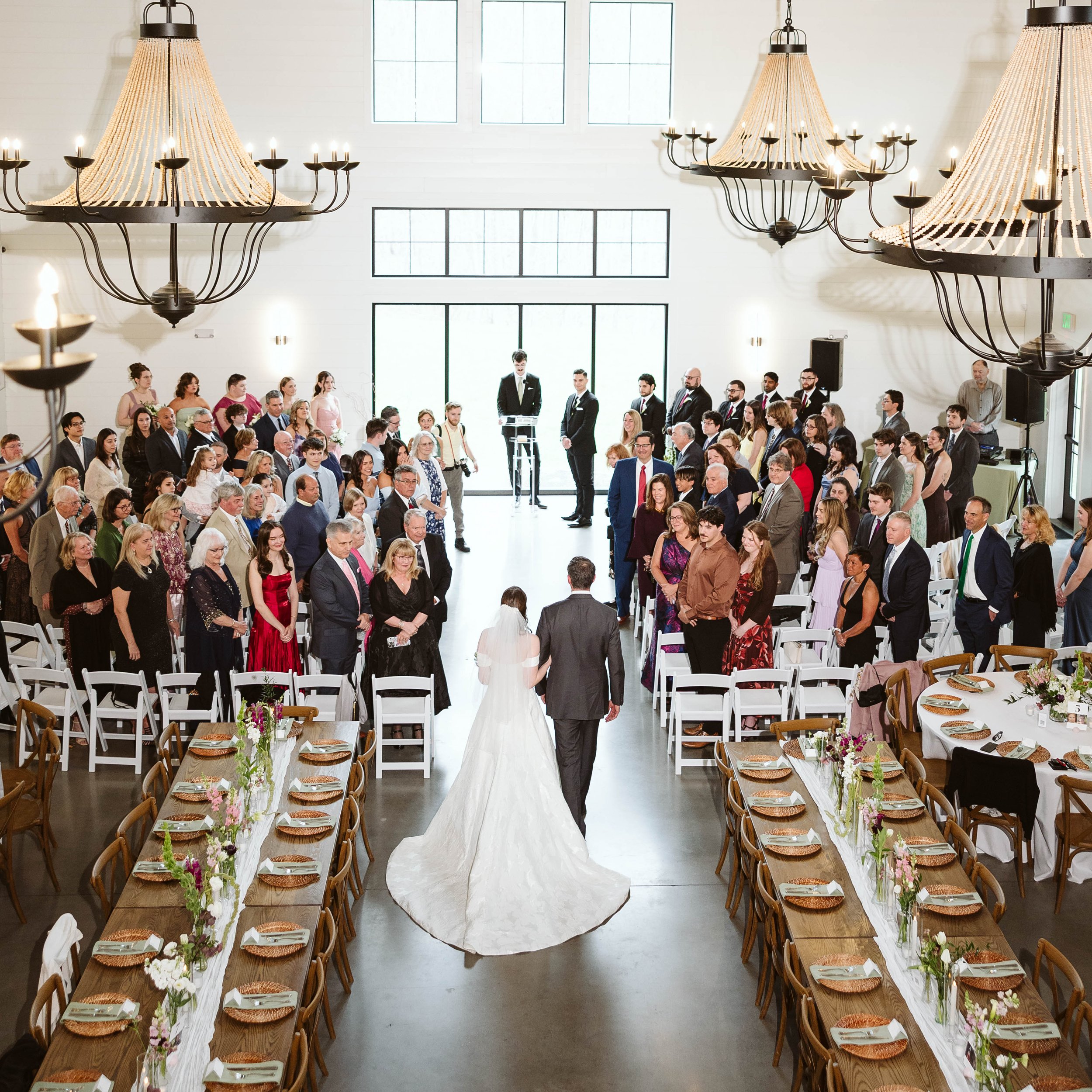 View from upstairs balcony of guests in seats as bride walks down the aisle. 