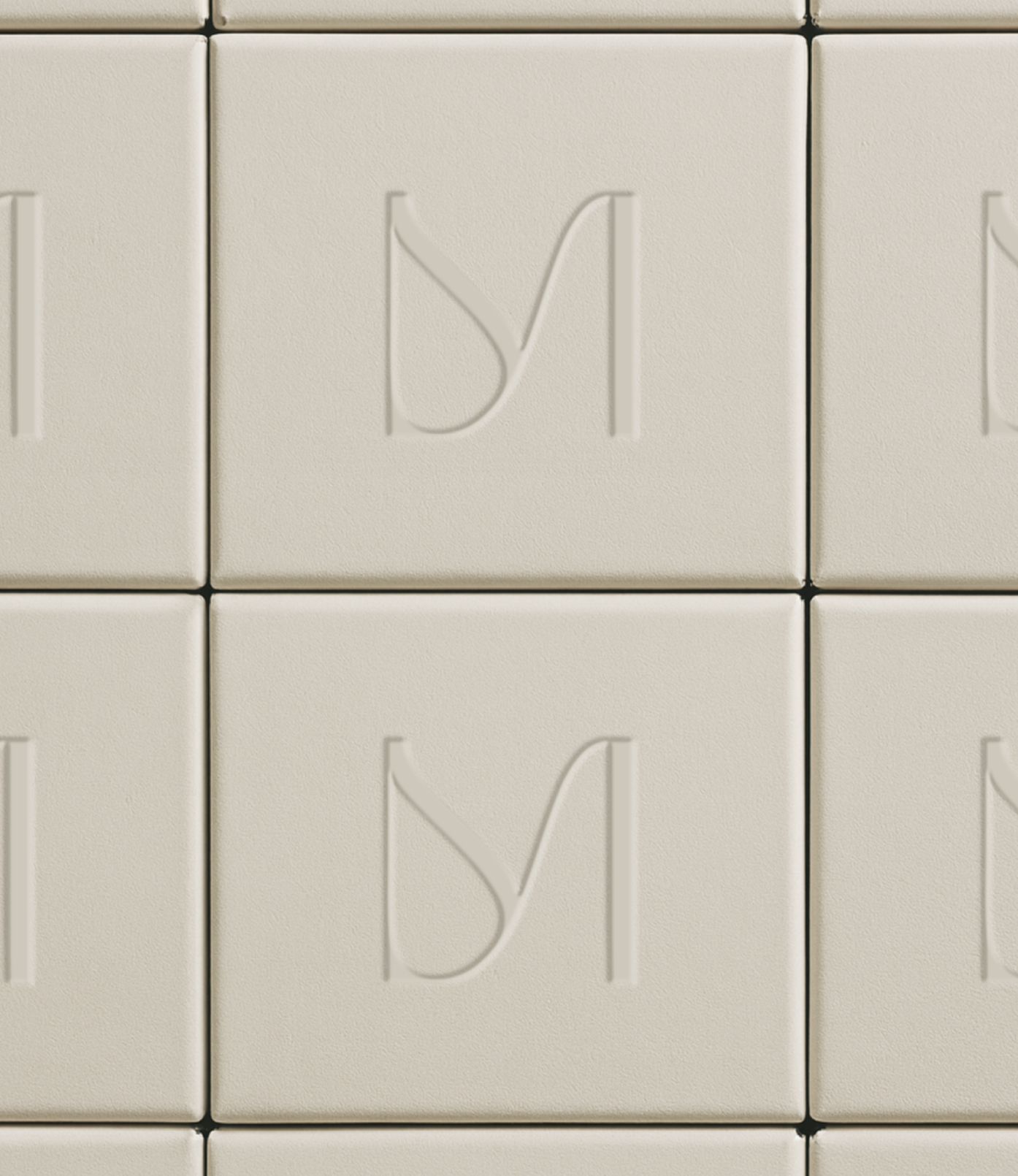 Close-up of beige textured tiles with embossed letter 'Y' and partially visible letter 'T'.