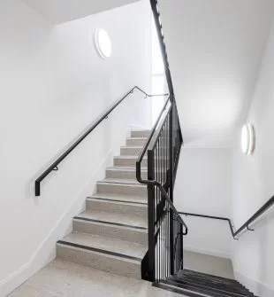 Indoor staircase with black handrails and white walls