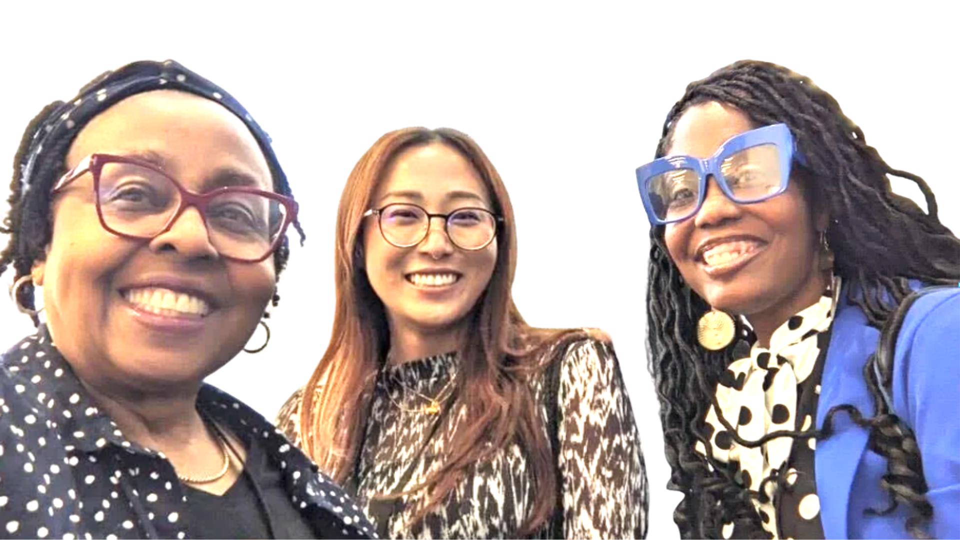Three women smiling for a selfie, dressed in colorful and patterned clothing, with glasses and enjoying a cheerful moment.