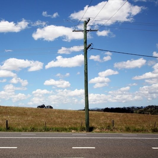 Telephone pole between a road and field