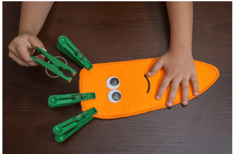 Toddler practicing fine motor skills by cutting paper, preparing for preschool readiness with scissor control.