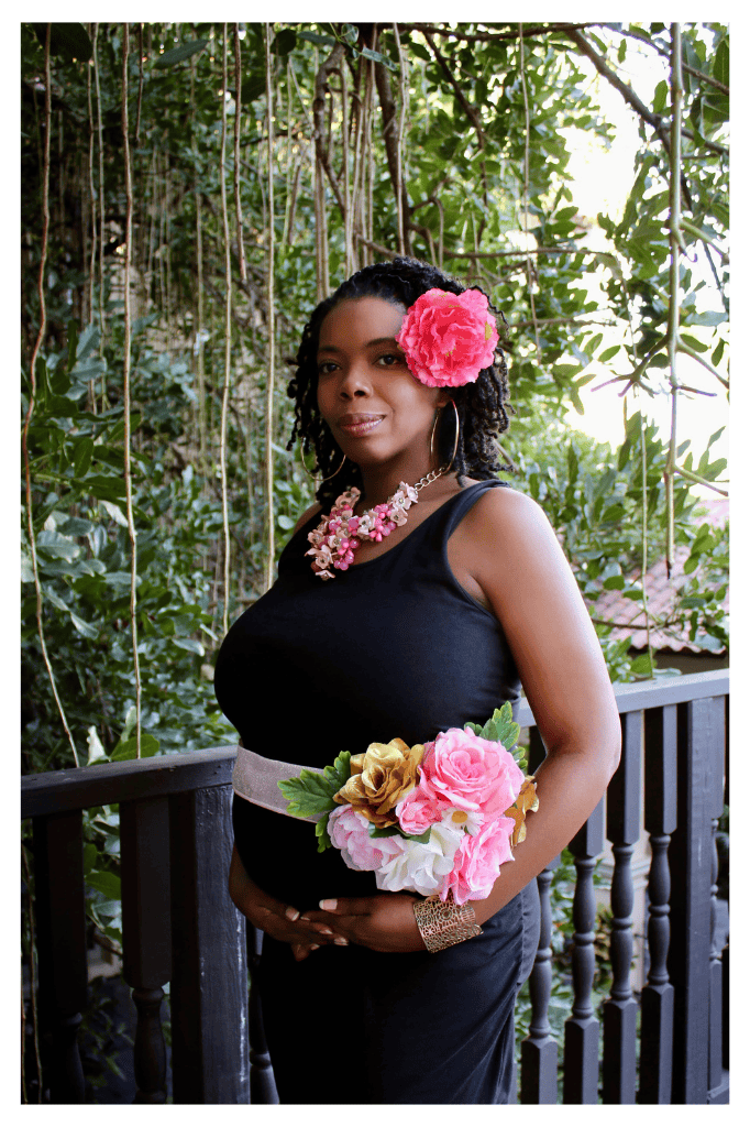 Pregnant woman in black dress with floral decorations on balcony