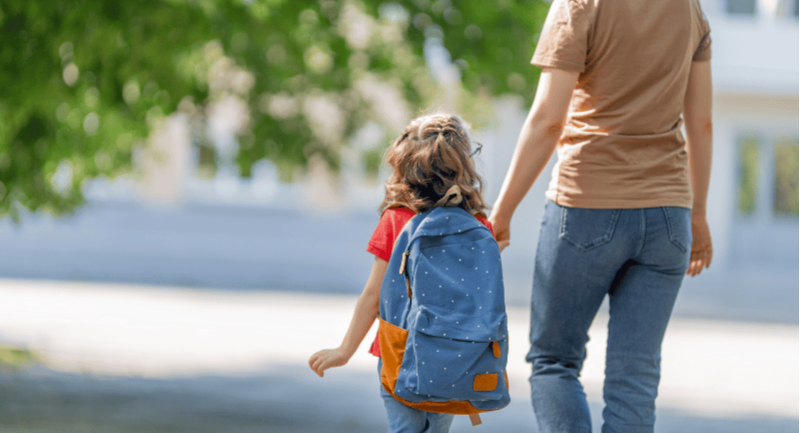 Mom holding hands with toddler during preschool morning drop-off routine to support school readiness and separation transition.