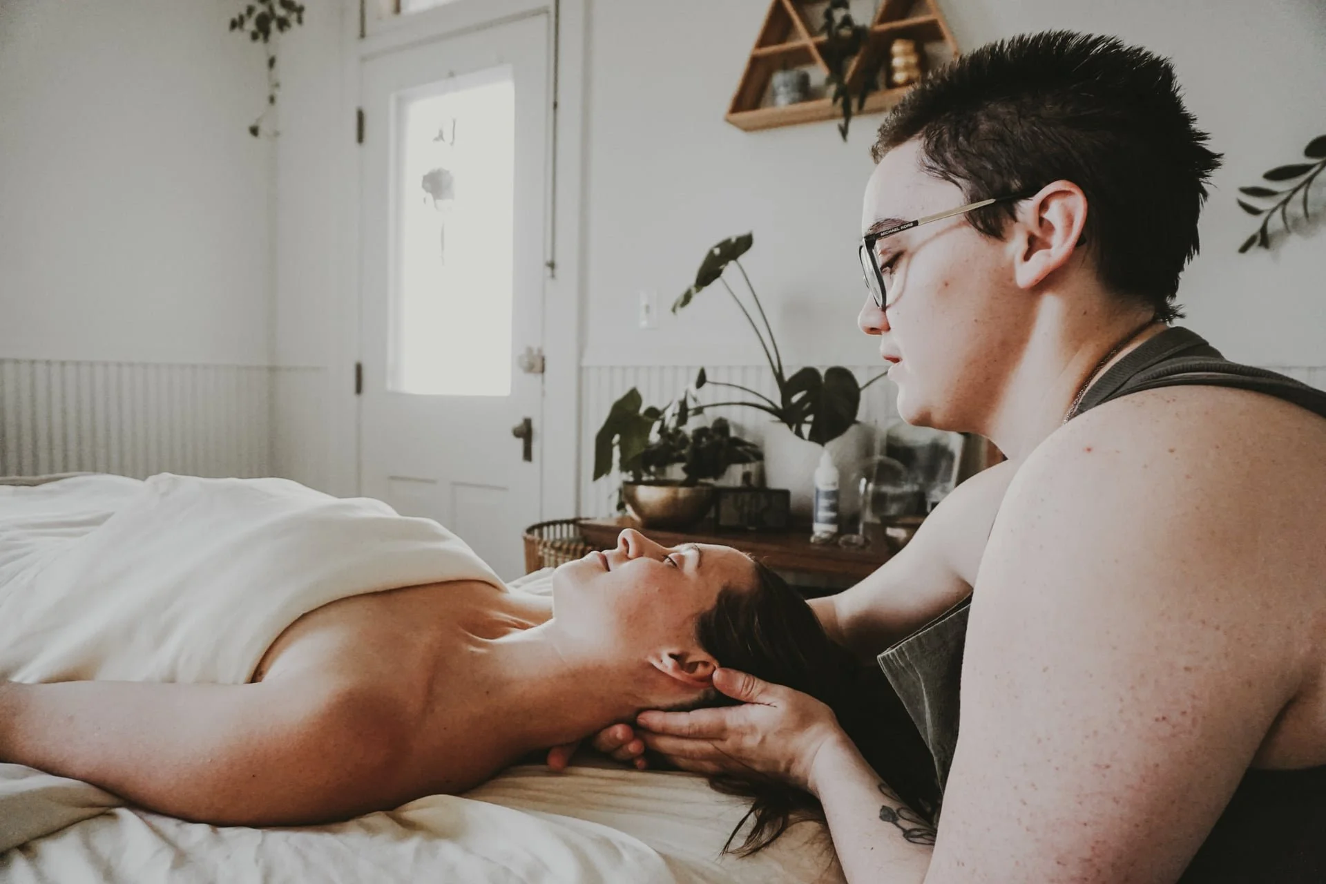 Massage thereapist stretching client neck in a calm natural lit massage room