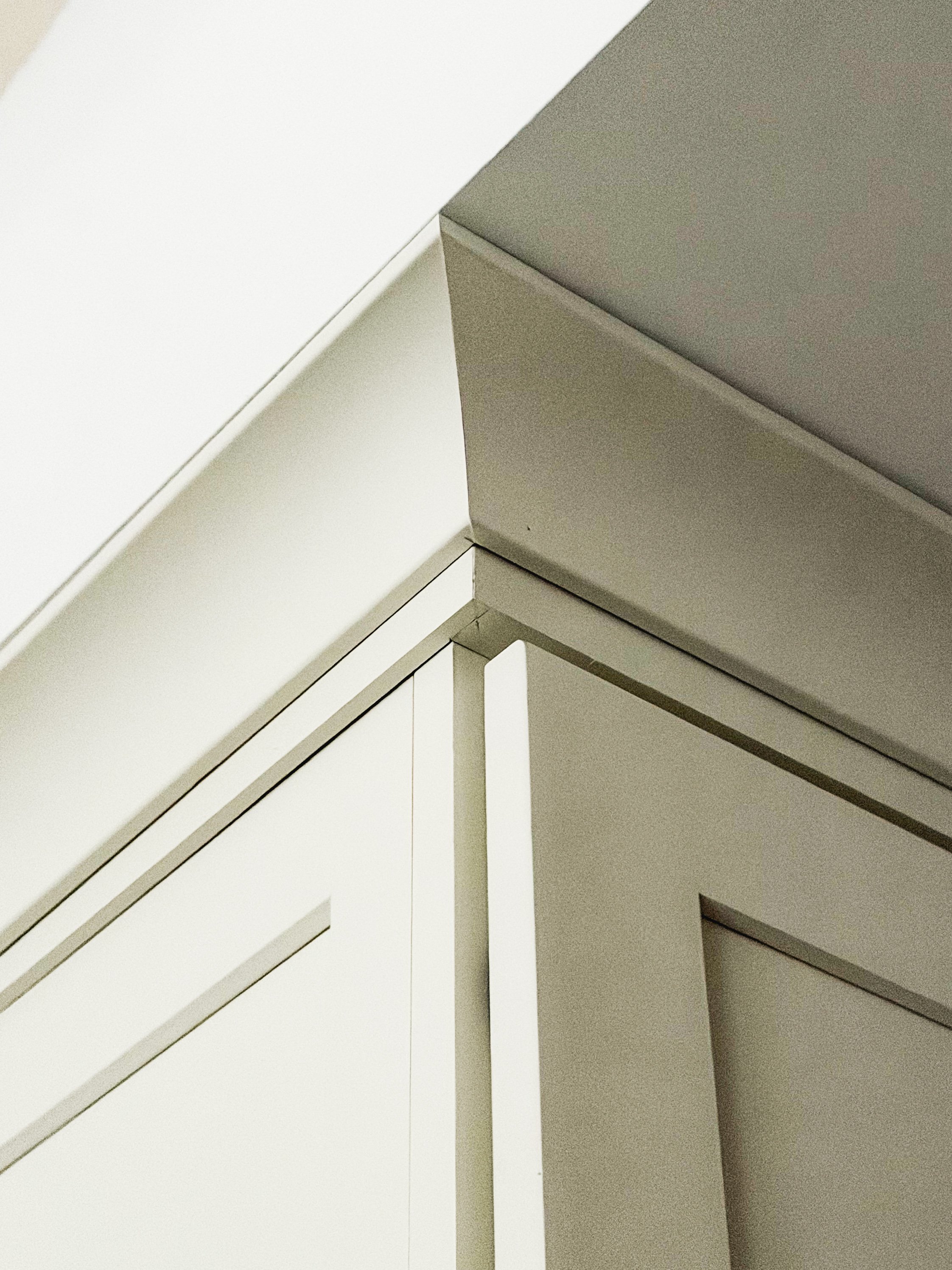 Close-up photo of a corner of white cabinets or furniture with clean lines and sharp edges.