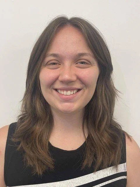 Woman smiling in a professional headshot wearing a black sleeveless top against a plain light background.
