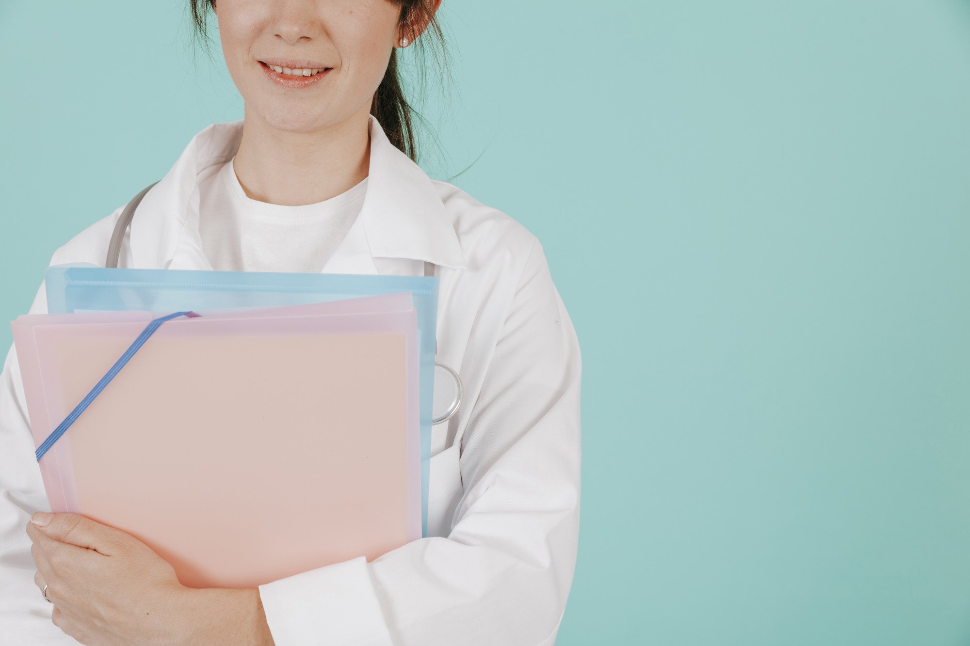 Doctor in a white coat holding folders against a light blue background.