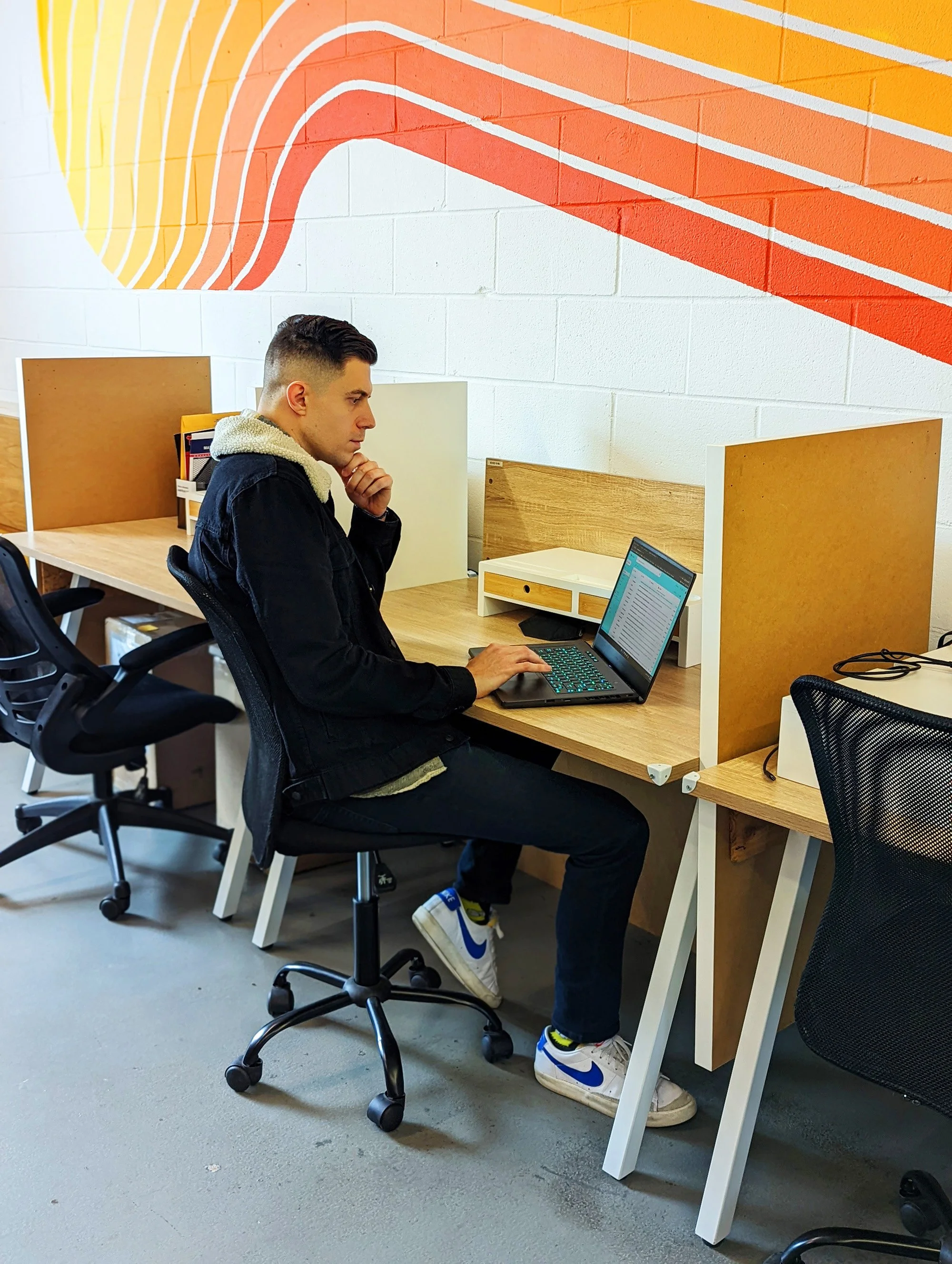 Austin creative working and seated with laptop at dedicated desk in a coworking space, Createscape, in east Austin.