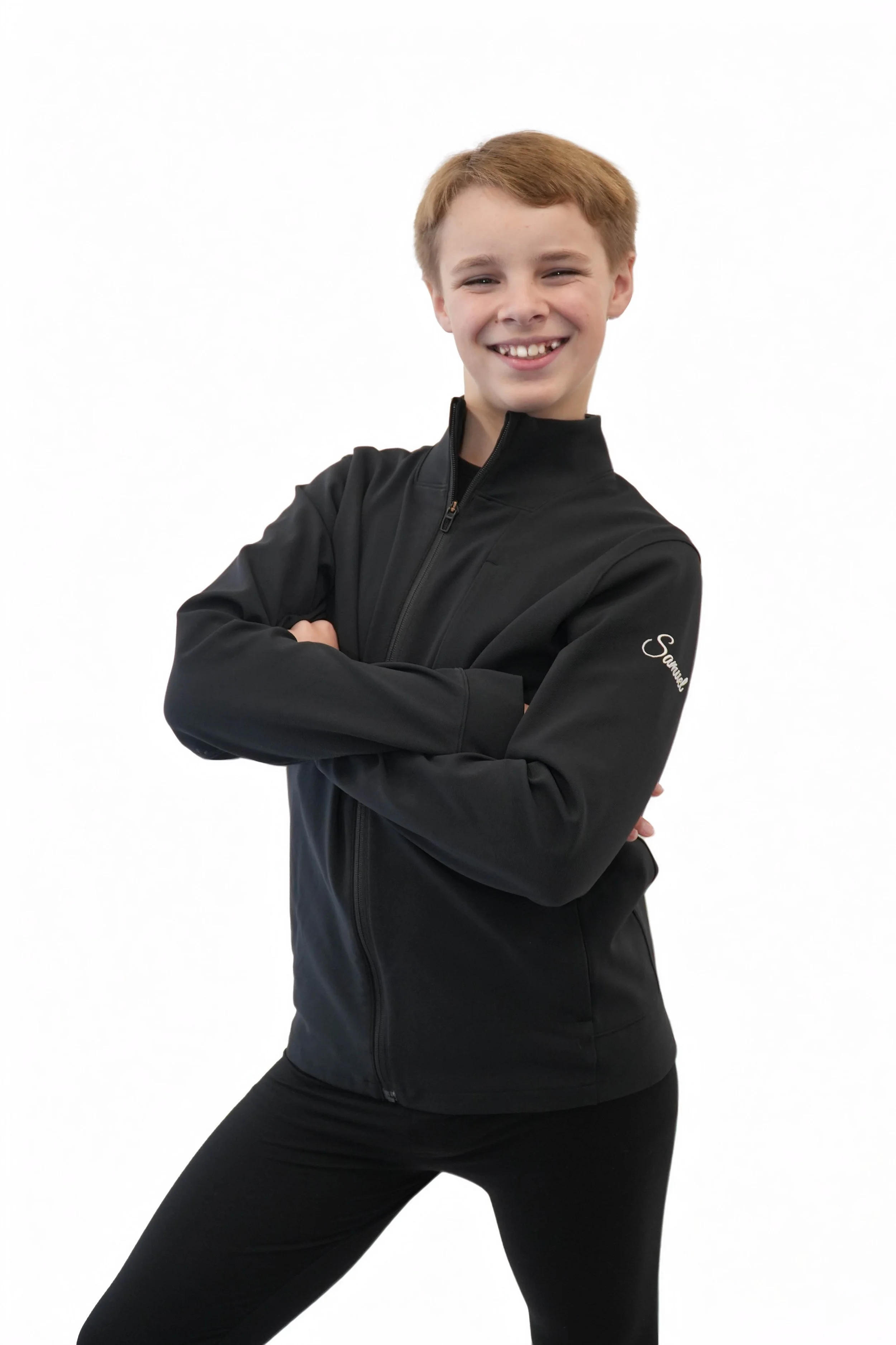 A young boy with light brown hair, standing with arms crossed, wearing a white zip-up hoodie and white pants, against a black background.