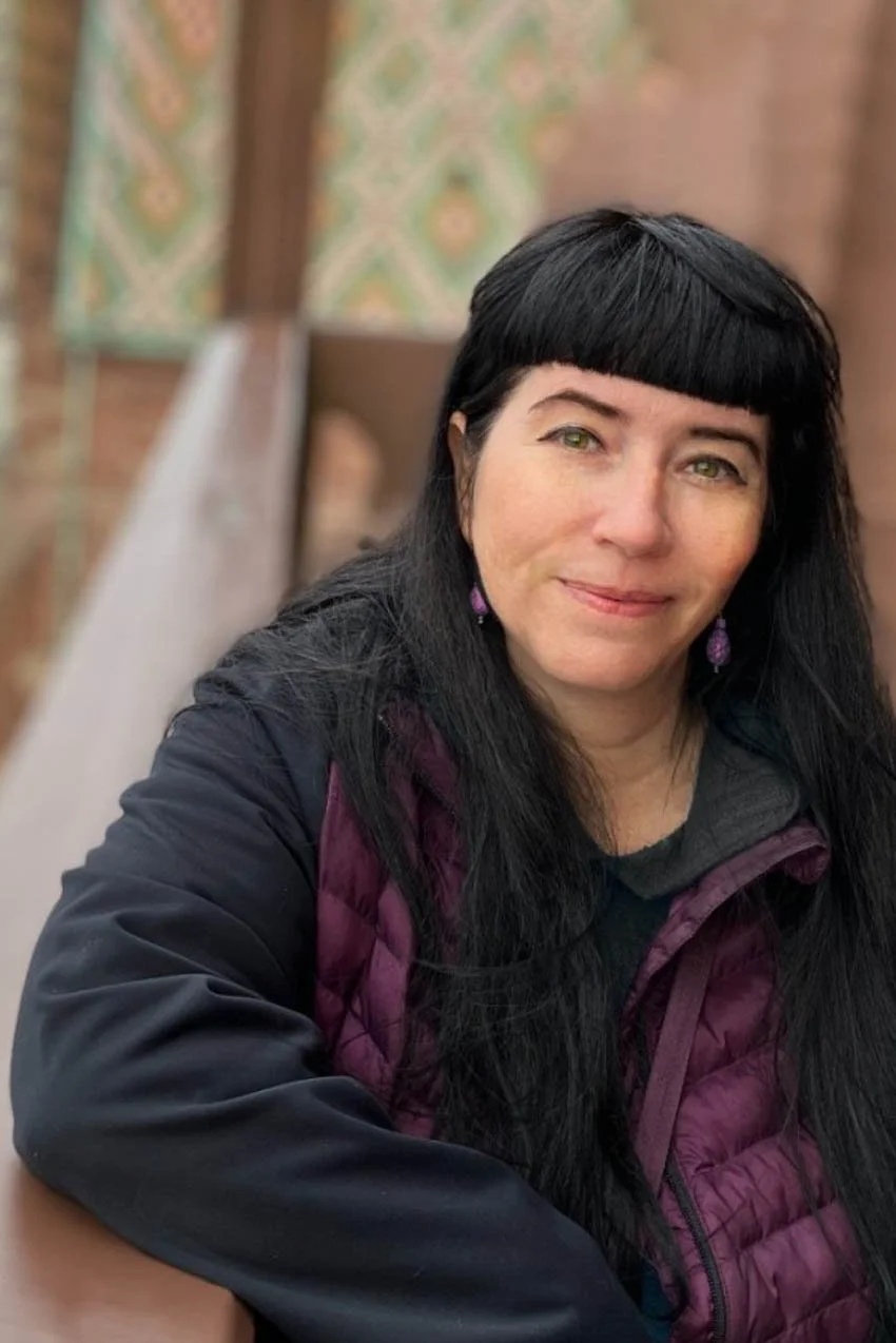 dark haired woman smiling in purple vest