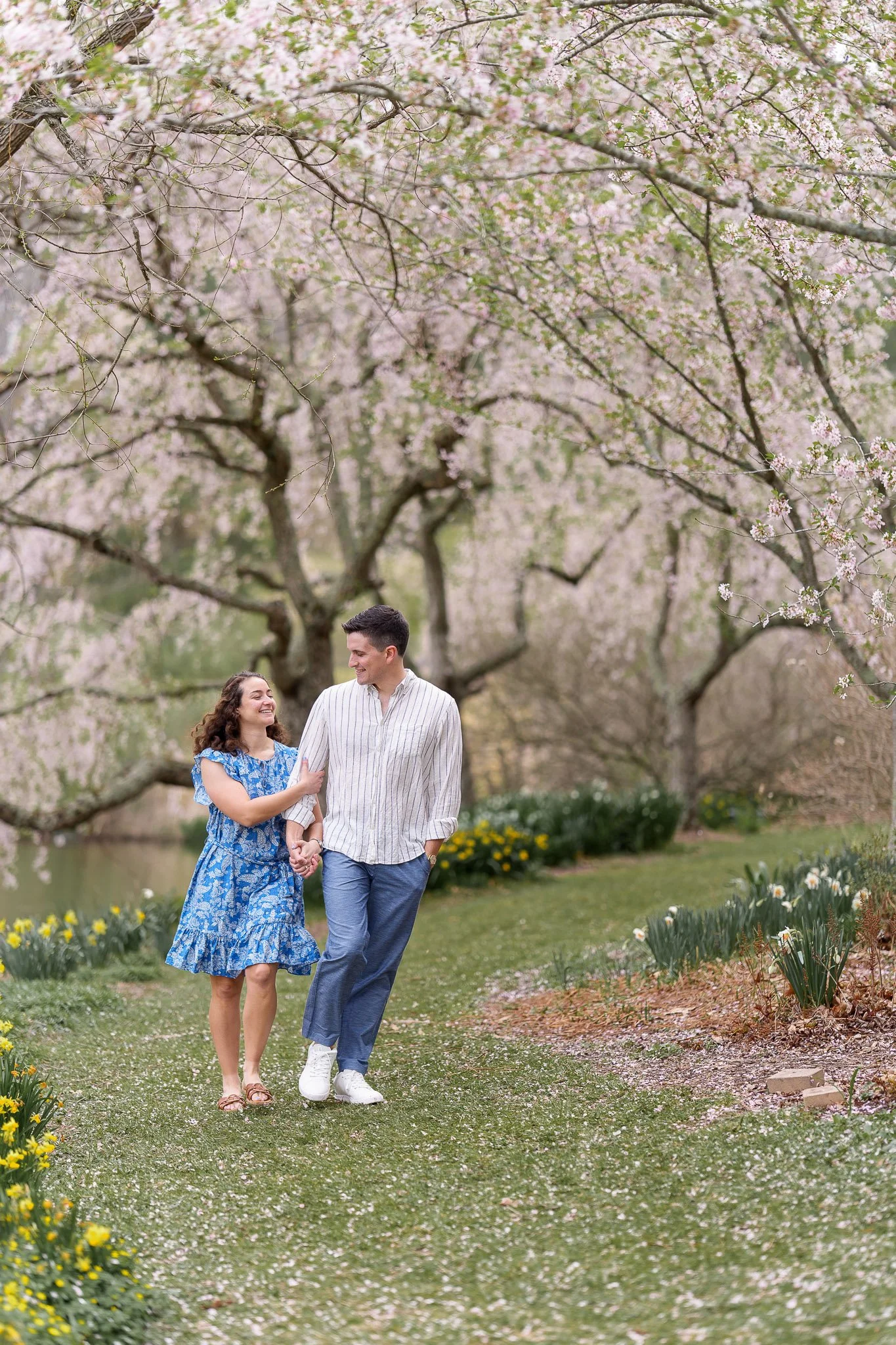 couple walking along a lake laughing and playing during a photoshoot