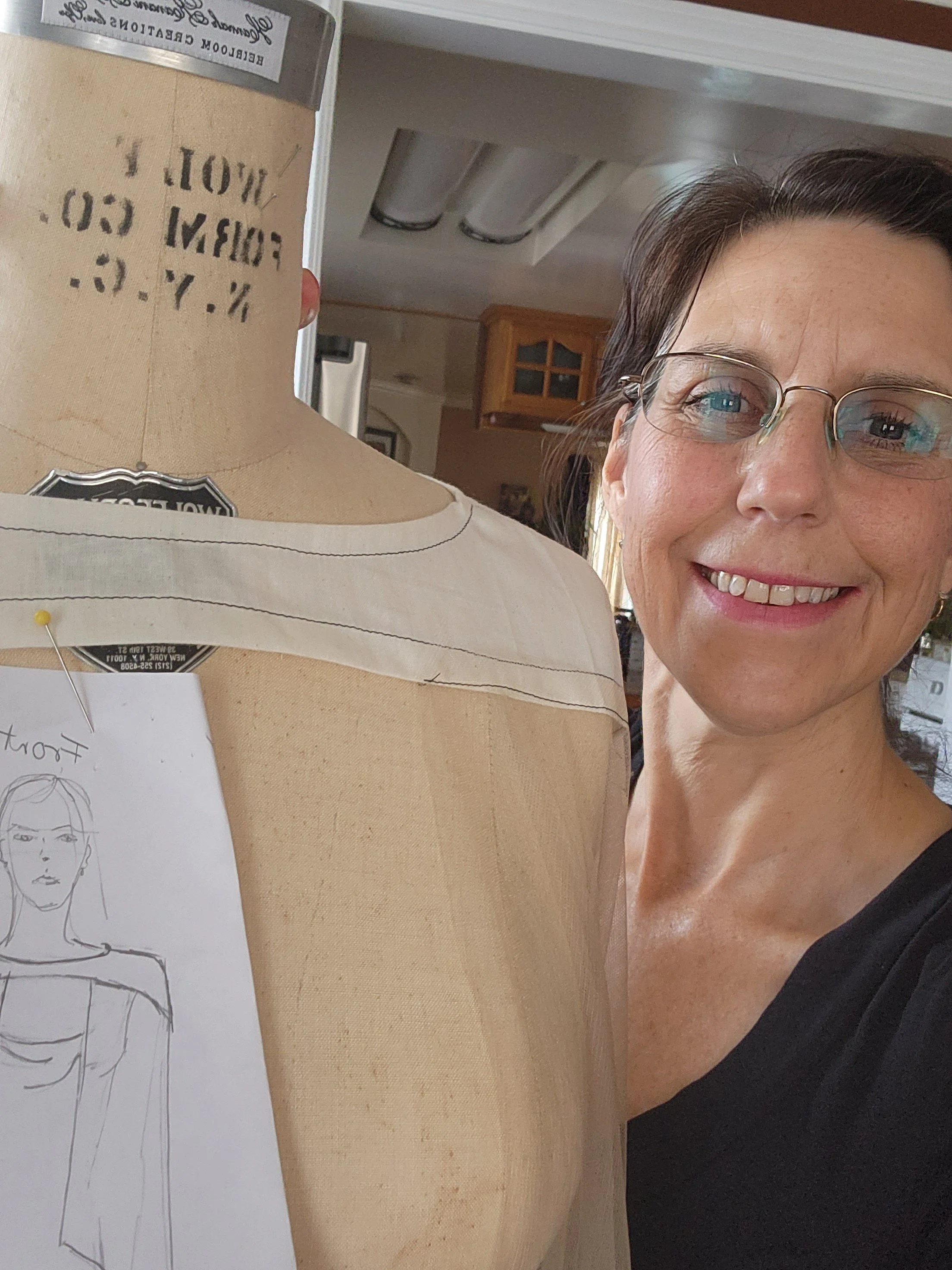 Bridal fashion designer Olga next to a dress form designing a bridal fashion cape