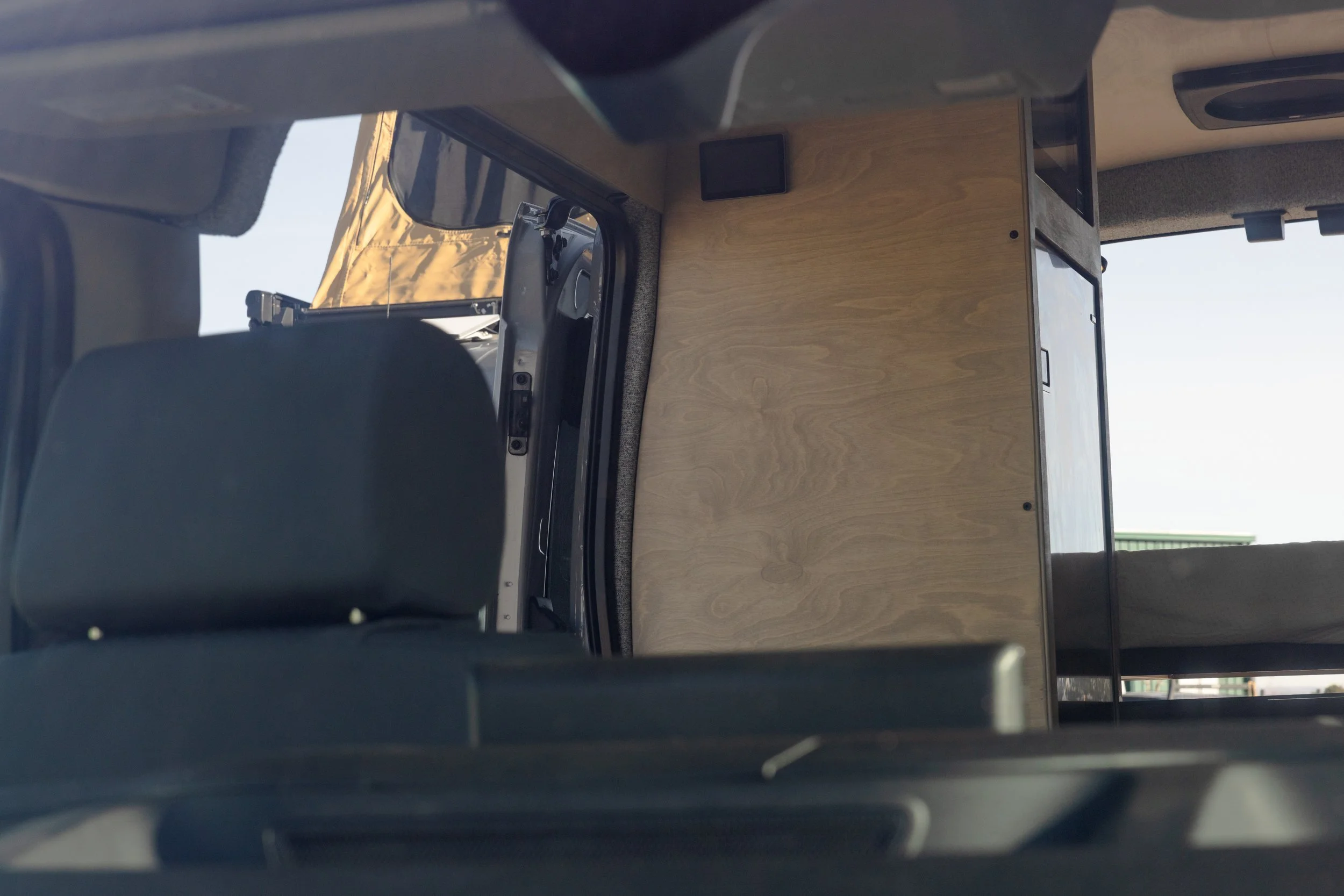 Inside of a vehicle with a wooden cabinet and a seating area, parked outdoors.