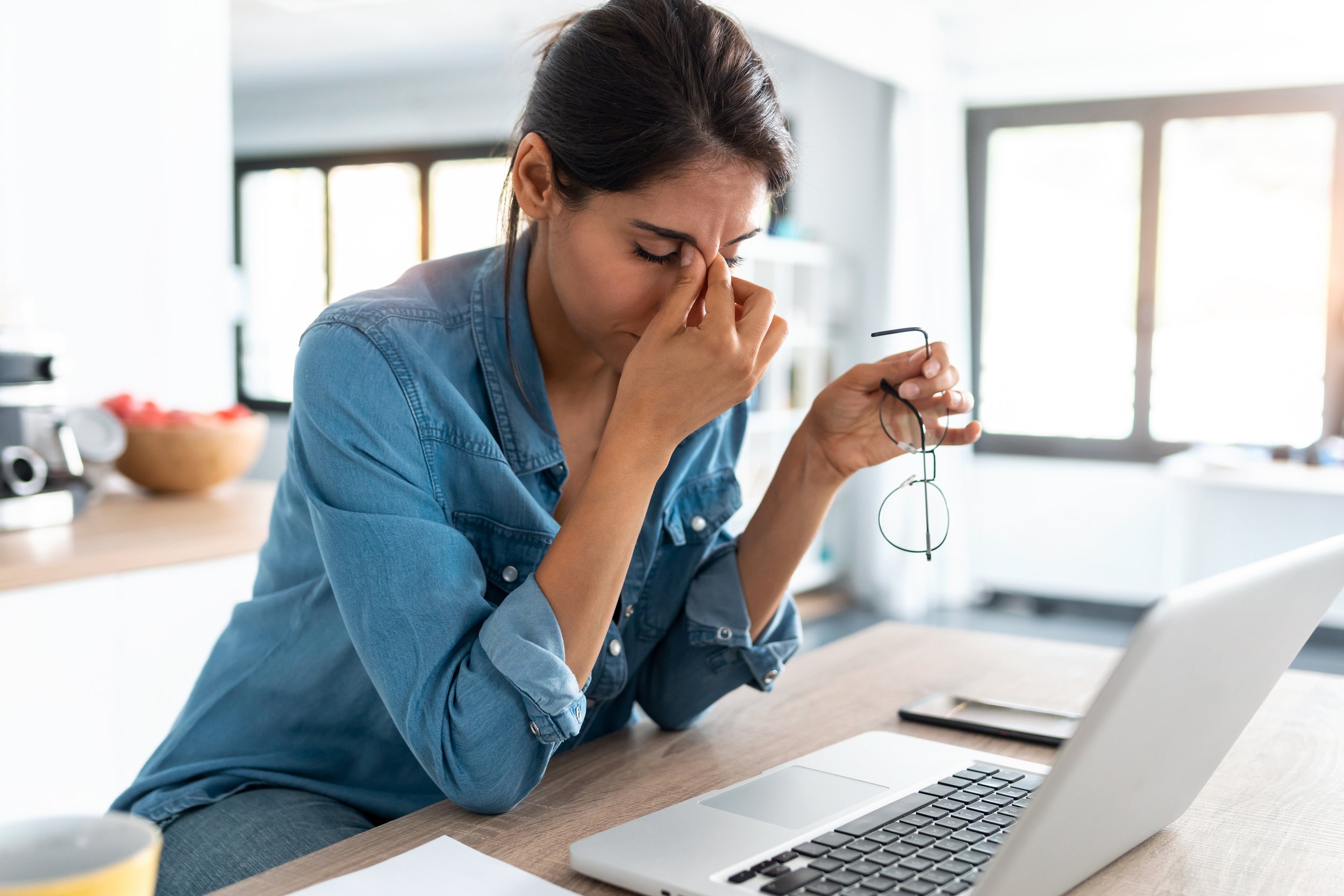 Woman at her work desk in front of a computer looking tired
