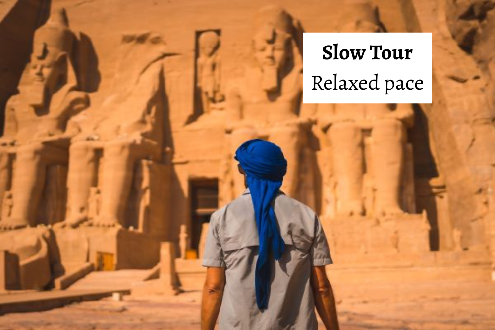 man with blue headscarf with his back facing the camera and looking otward the front facade of Abu Simbel 