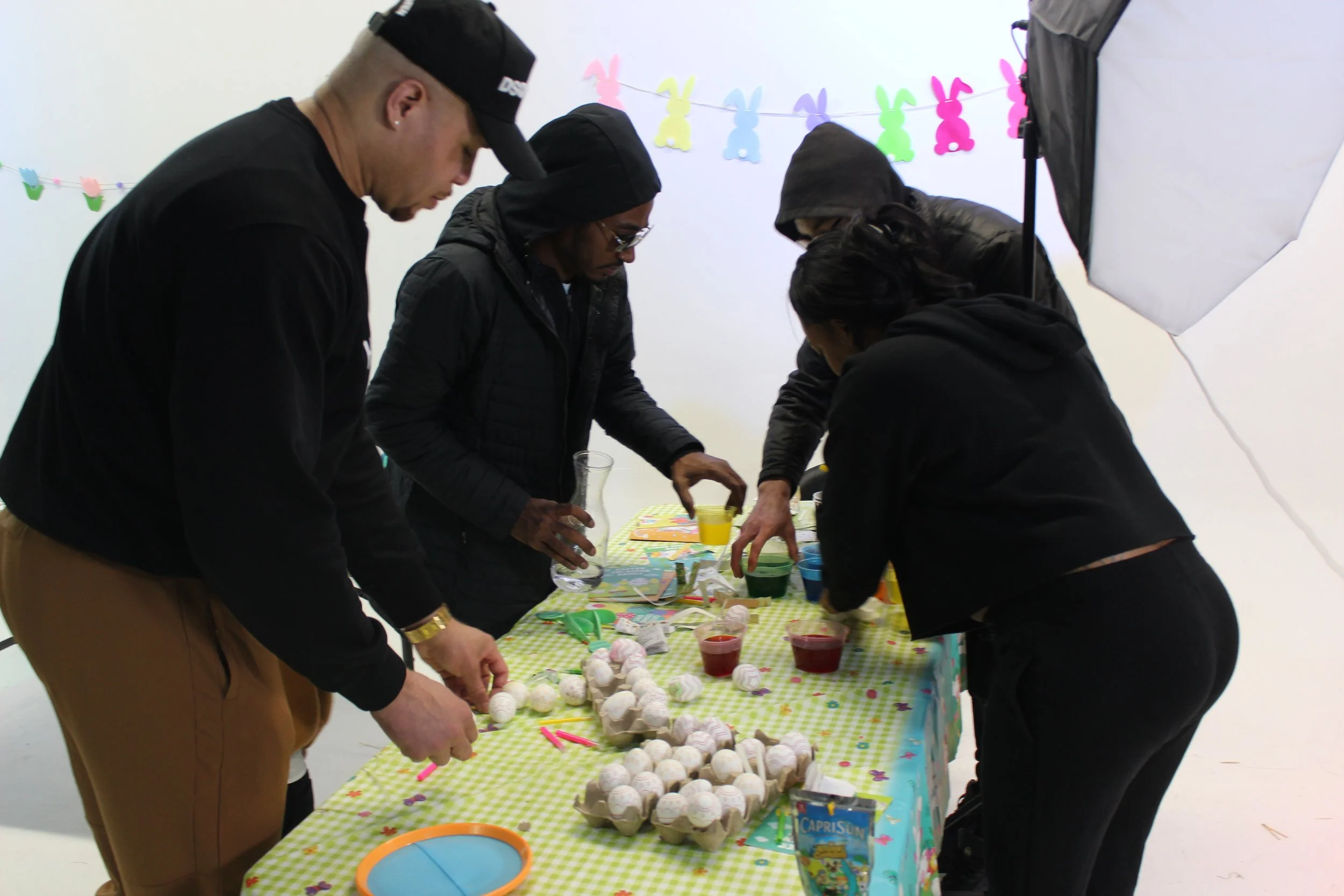 People gathered around a table with Easter-themed decorations, preparing treats and snacks for an Easter celebration.