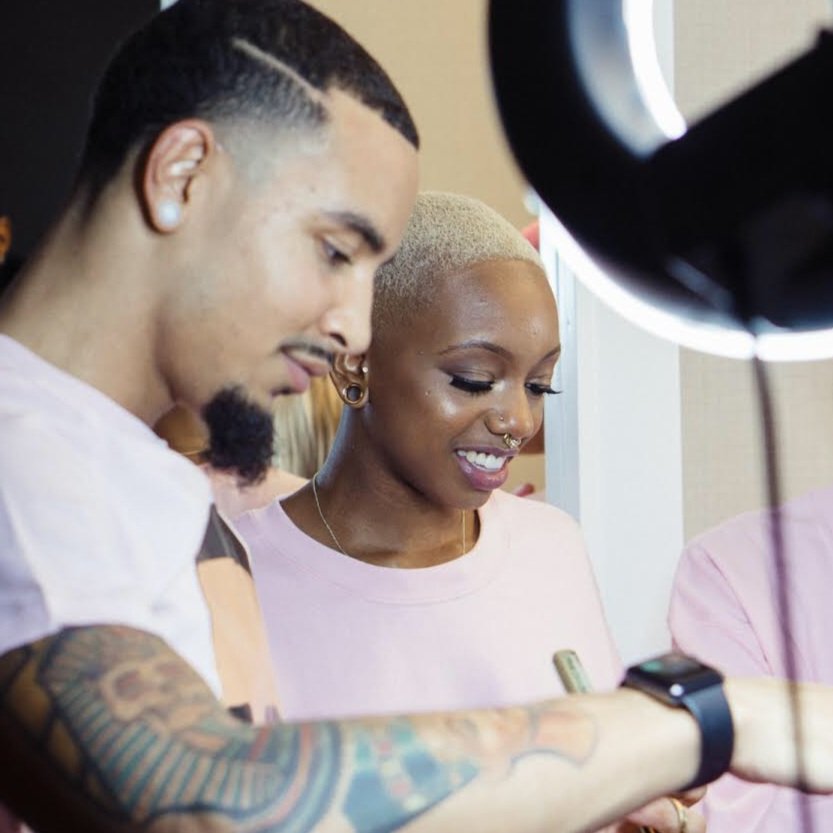 A man with tattoos and a woman with a short blonde haircut looking at something together during a tattoo session.