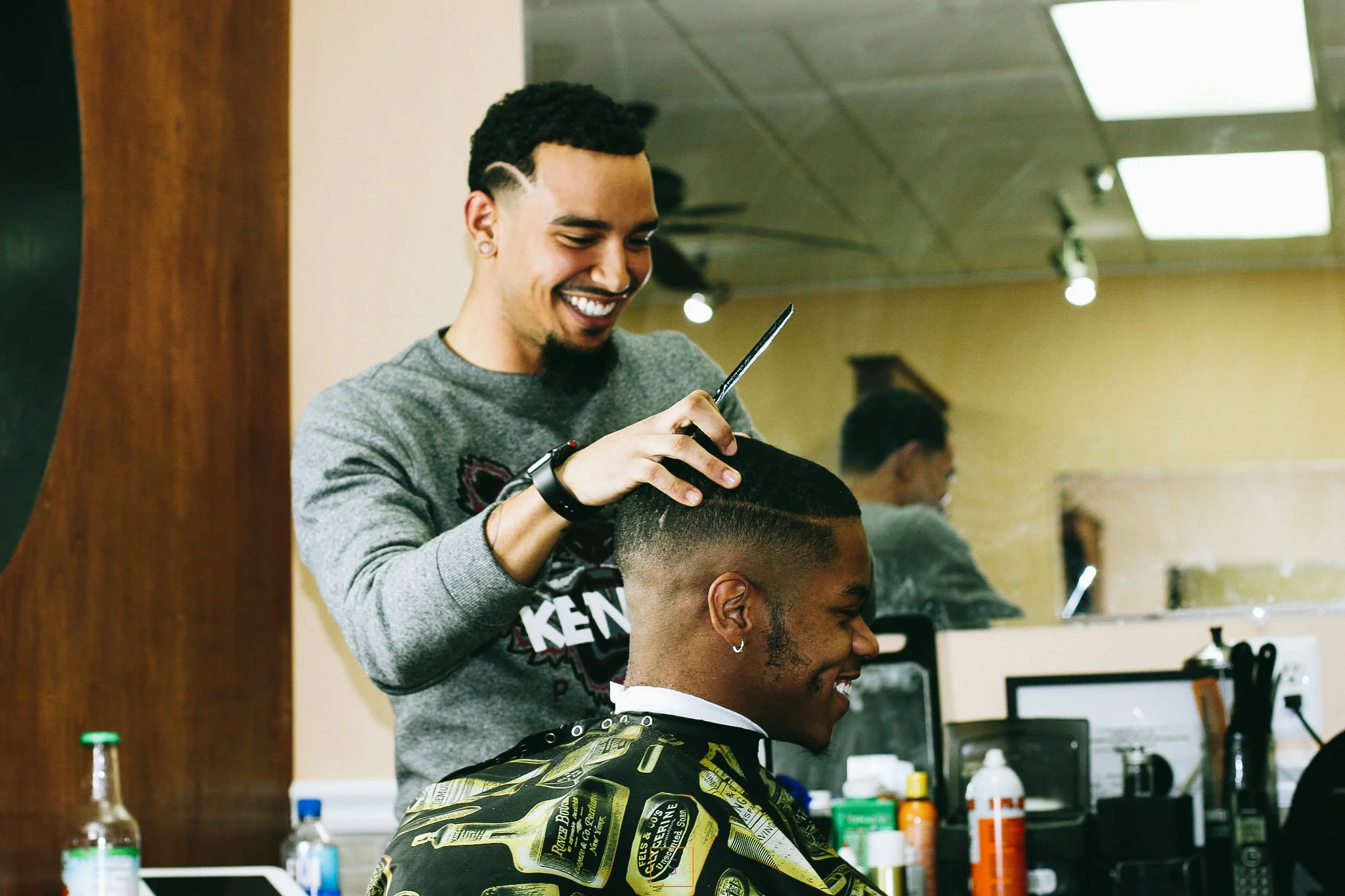 Barber giving a haircut to a smiling client in a barbershop.