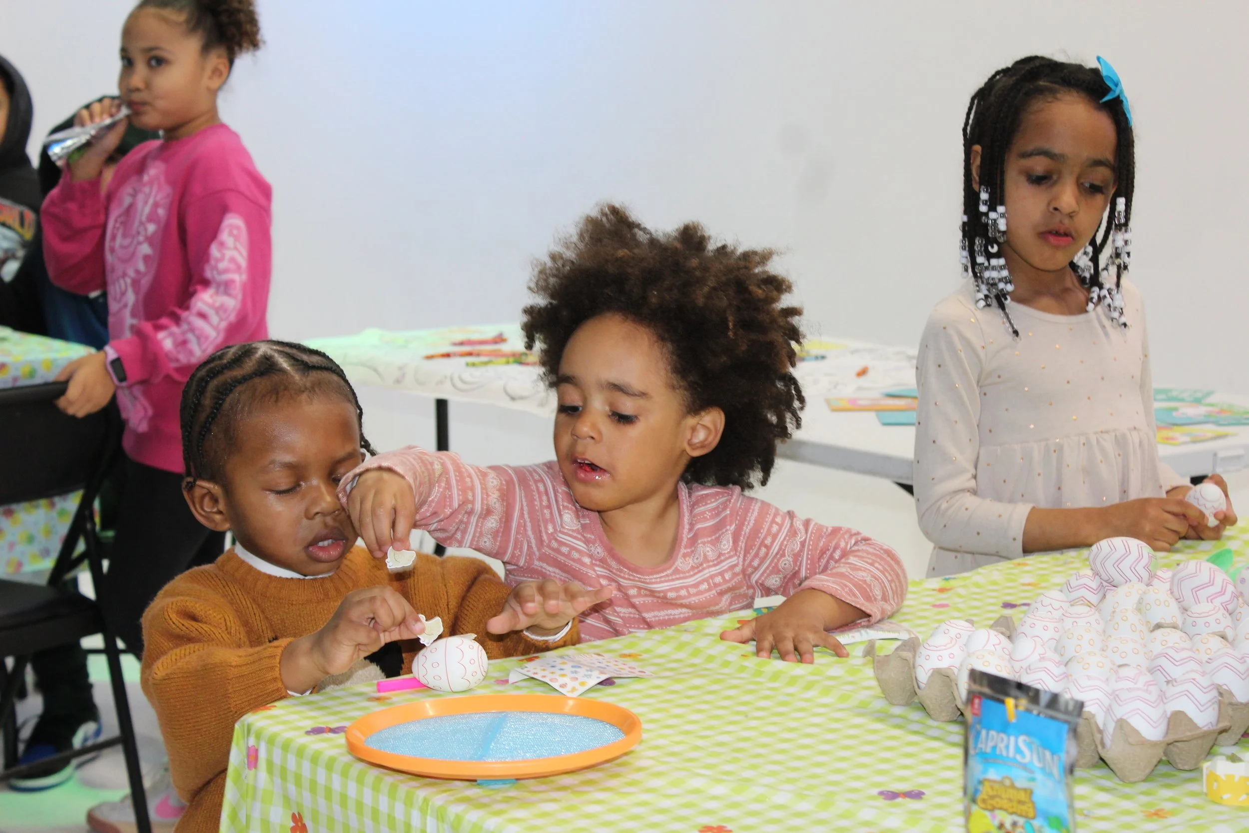 Children decorating Easter eggs at a festive table.