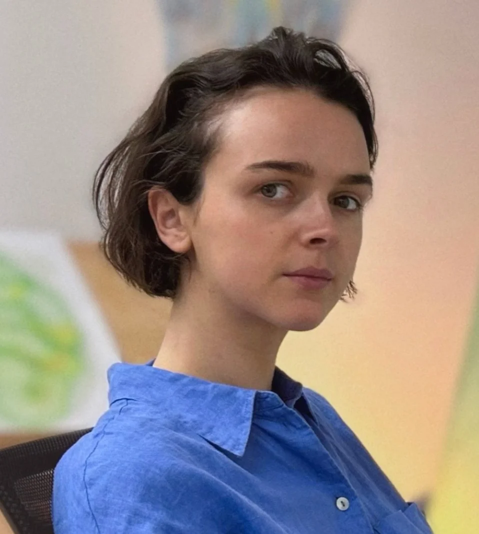 A woman with short dark hair wearing a blue button-up shirt looking at the camera.