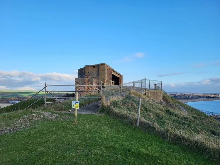 Old brick bunker on a grassy hill near a coast