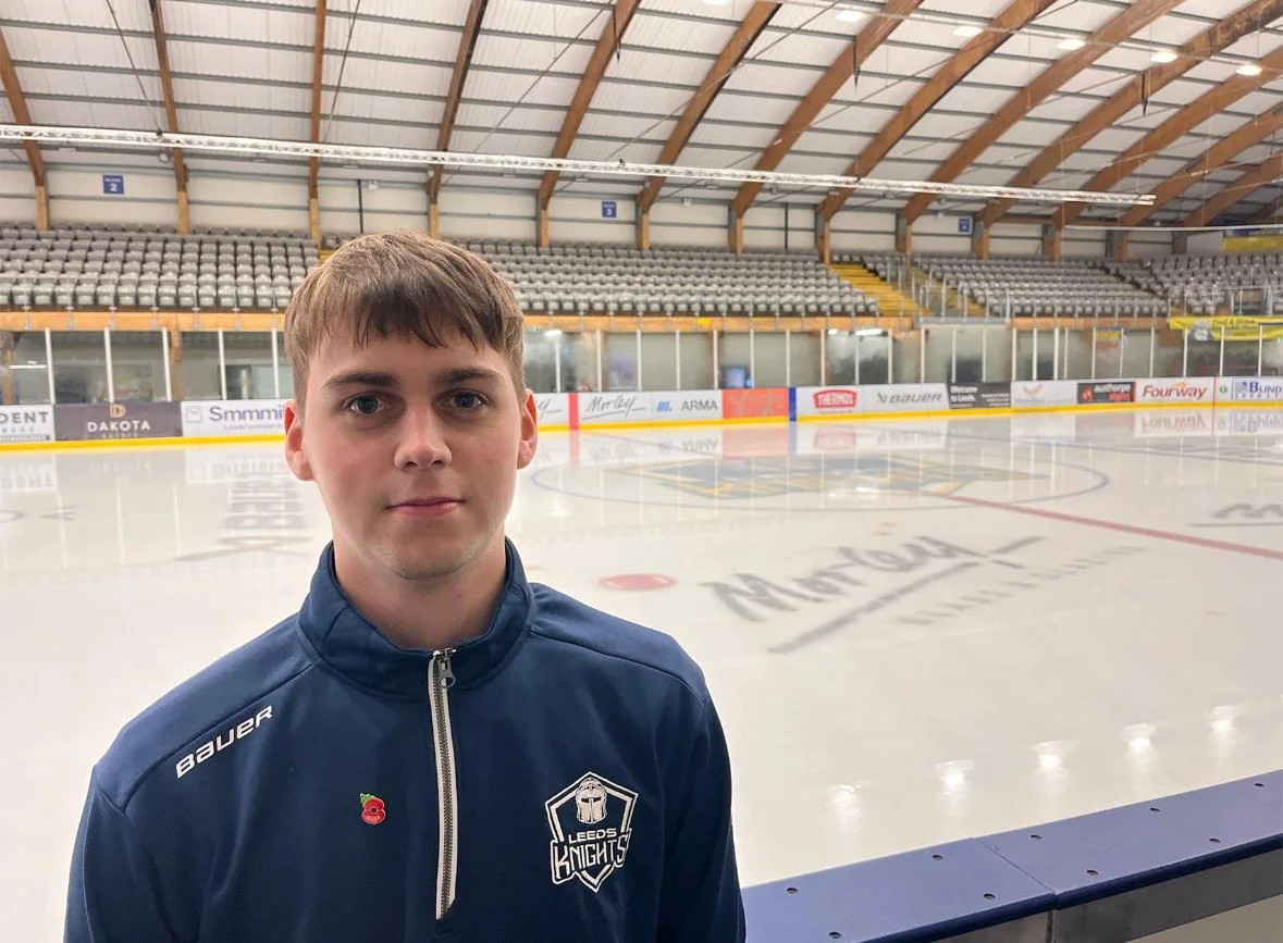 Young man in a Leeds Knights jacket standing at an ice hockey rink.