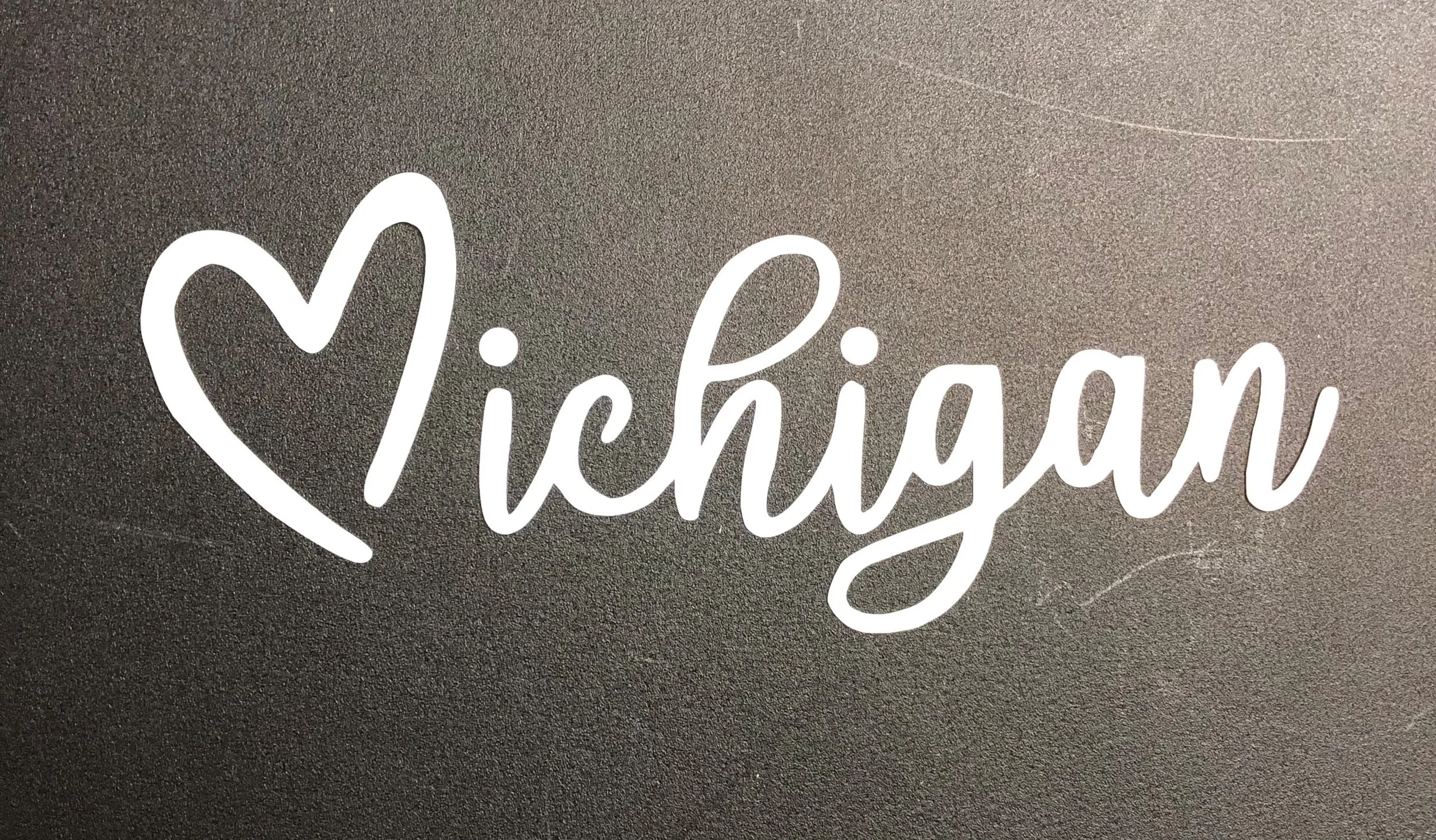 A black surface with white cursive text that reads 'I ❤️ michigan'.
