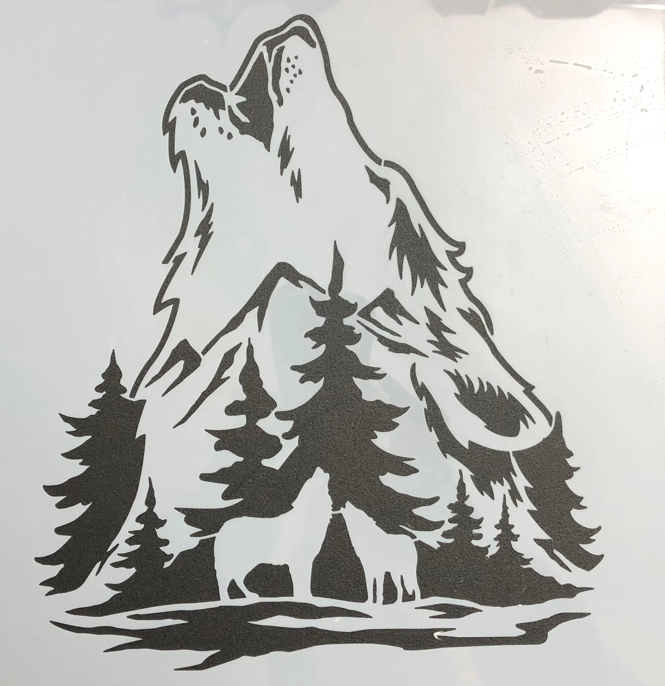 Silhouette of a mountain, trees, two bears, and a compass in black on a white background