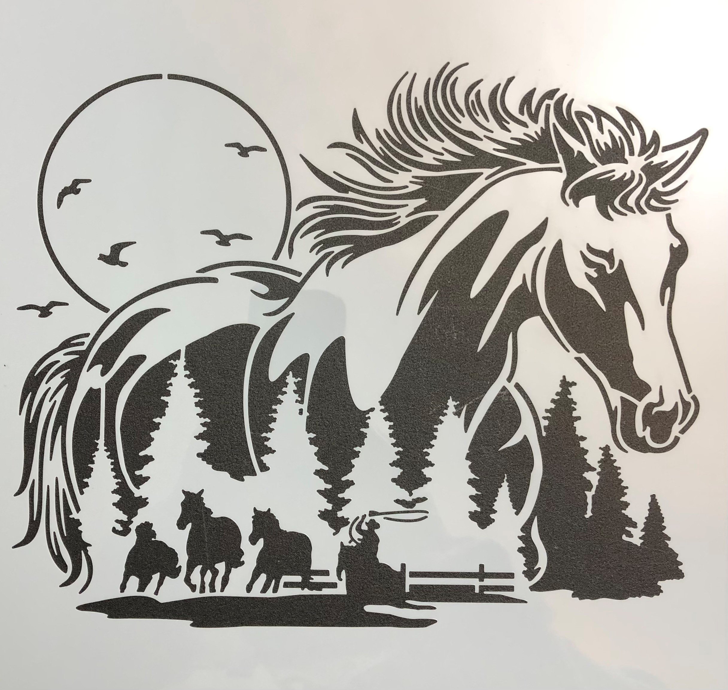 Silhouette of a horse's head over a natural landscape with trees, a flock of birds, and a setting or rising sun.