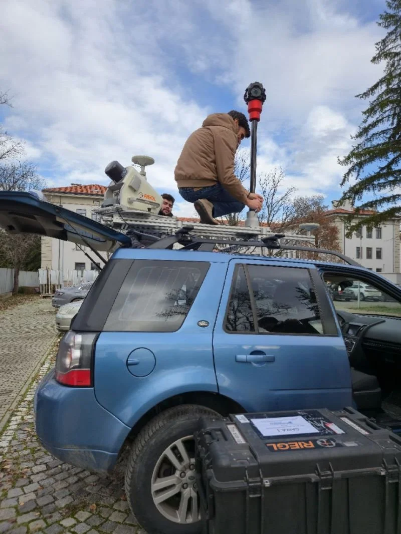 A mobile LIDAR scanner and camera being mounted on the roof rack of a car by the MYX team, November 2025