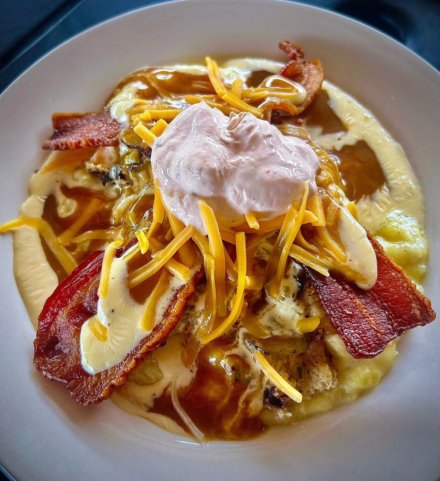 KITCHEN SINK: a bed of caraway smashed potatoes topped with a turkey burger and loaded with green chile, gouda jalapeno cheese sauce, gravy, cheddar cheese, bacon, and sriracha sour cream. 

#TheCrowsNestSTL #MaplewoodMO #StLouisEats #NewMenu #Comfor