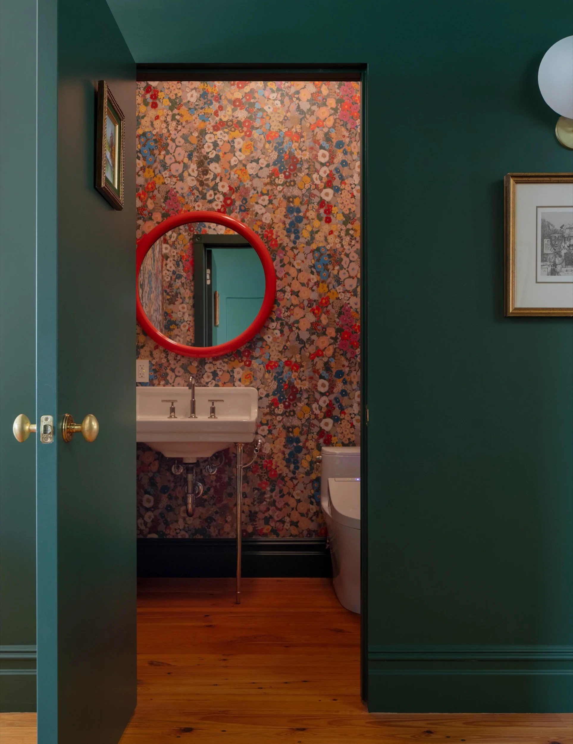 Powder room with floral wallpaper and red mirror