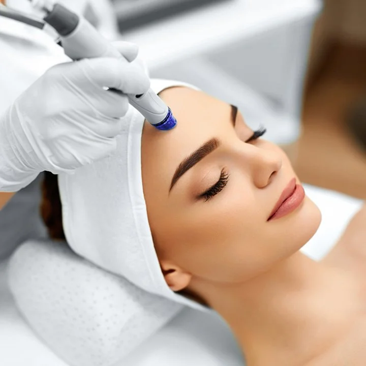 A woman receiving a facial treatment with a device on her forehead in a spa or cosmetic clinic