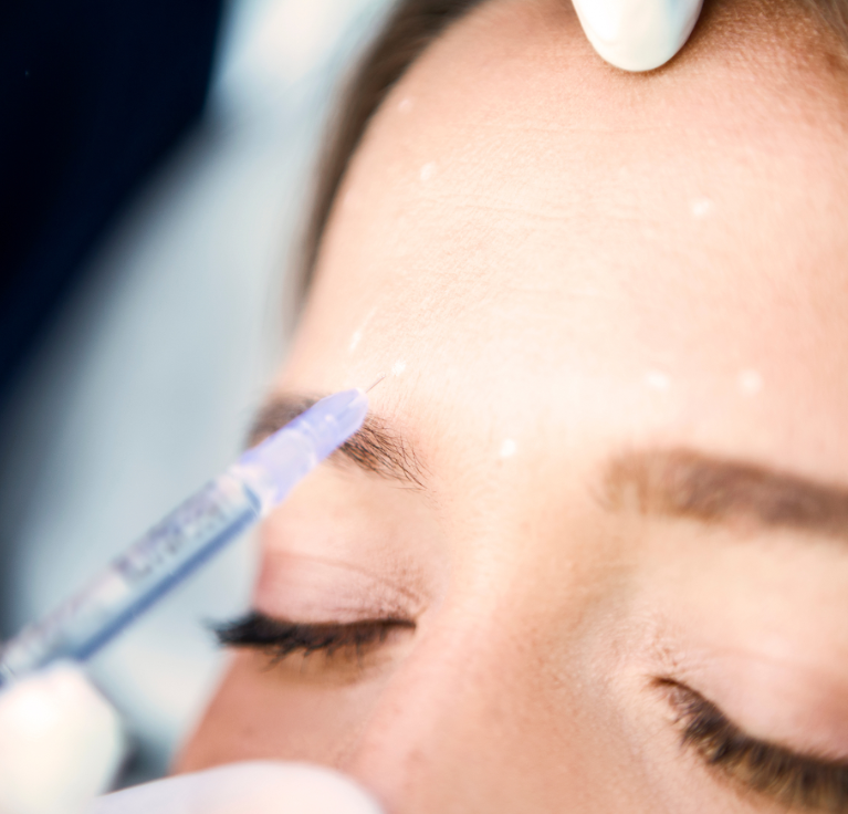 Cosmetic procedure being performed on a woman's eyebrow, with a close-up view of her face and closed eyes.