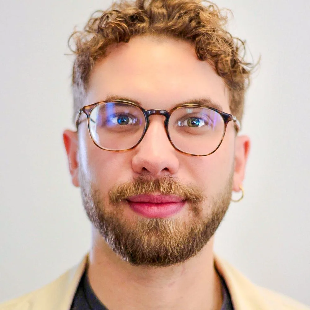 Guilherme Boller, de cabelo cacheado, óculos e barba