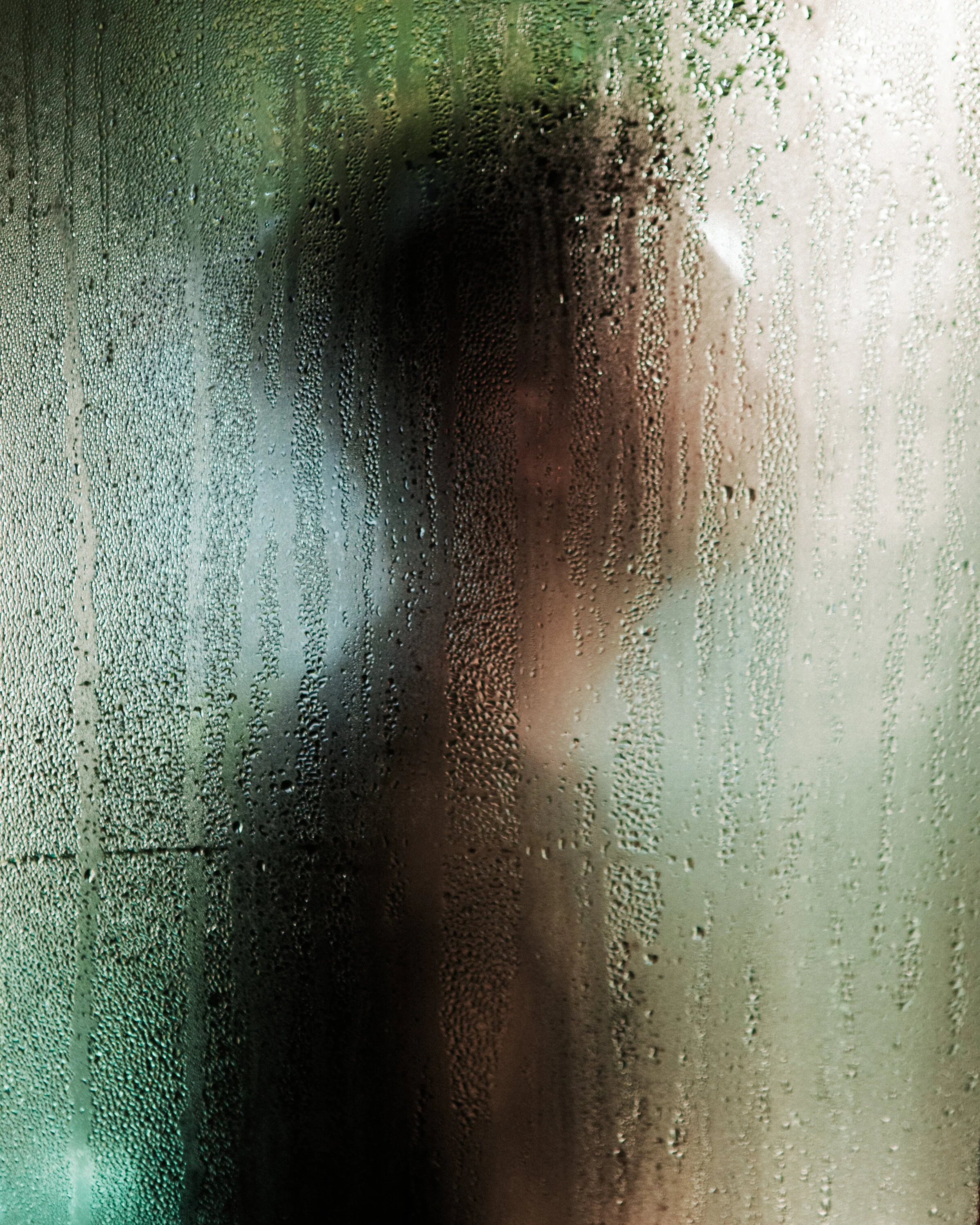 Close-up view of a foggy glass window covered with condensation and water droplets.