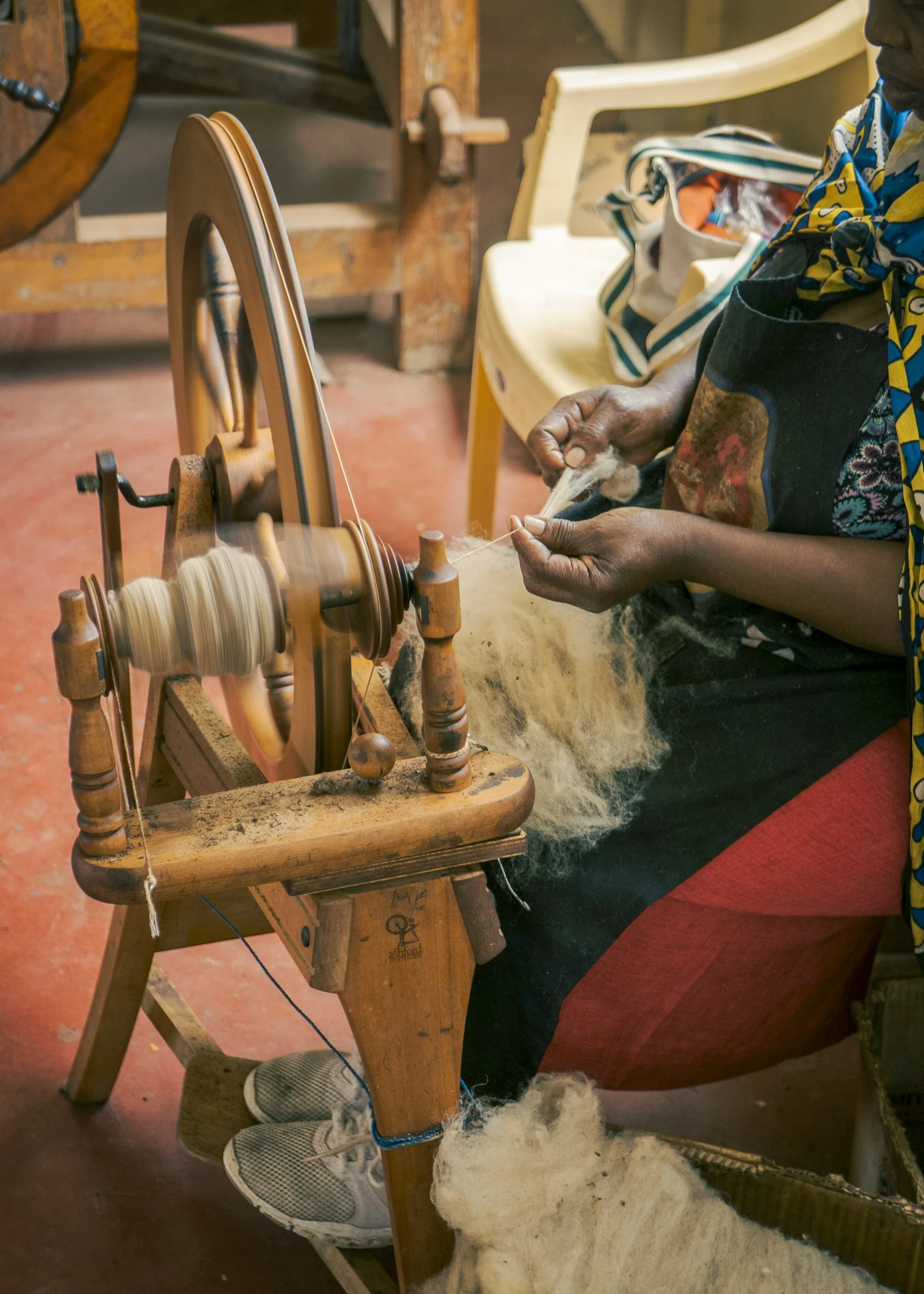 A person spinning wool into yarn using a spinning wheel.