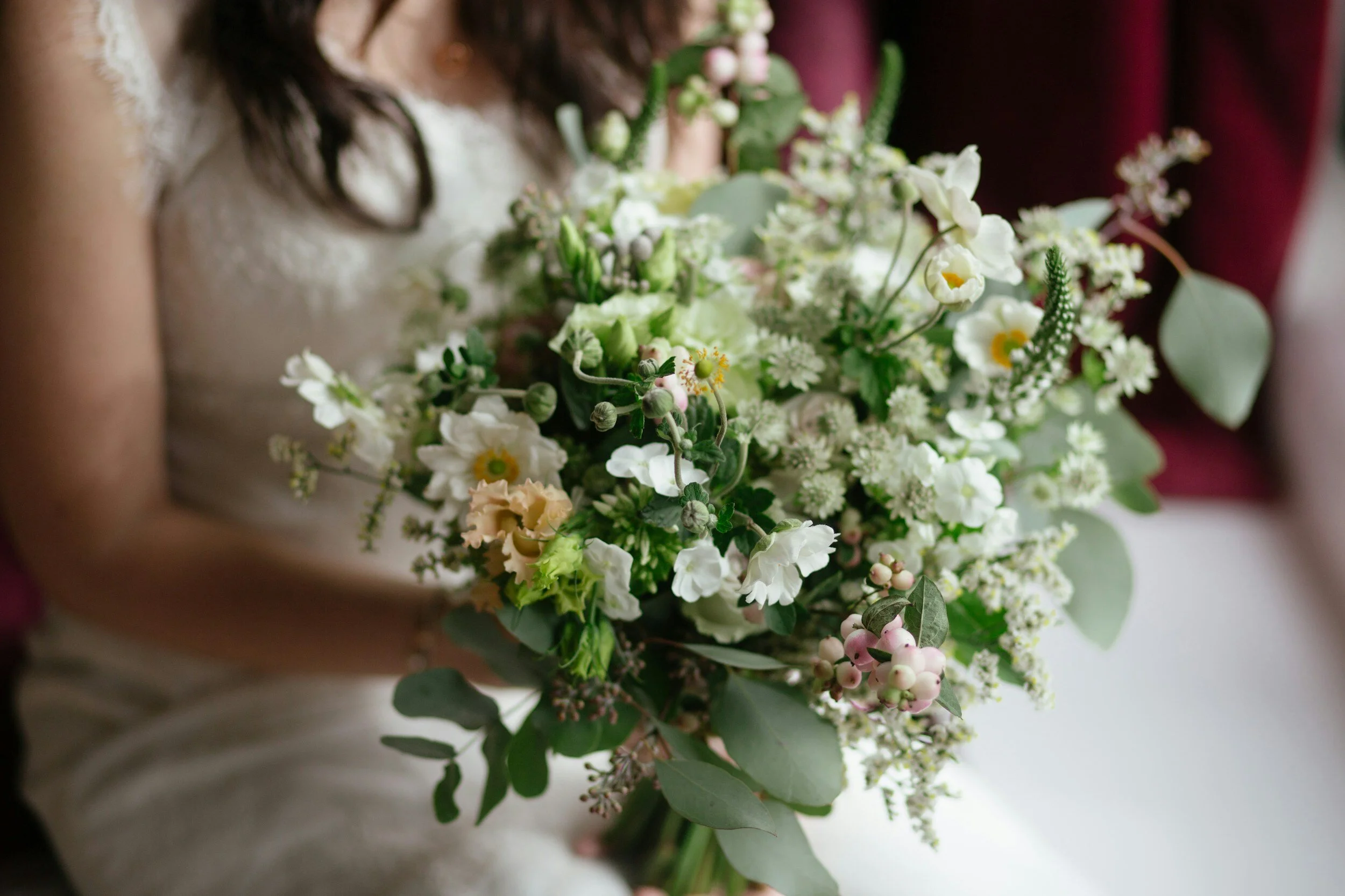 Bride holding a bouquet of white and pink flowers with green eucalyptus leaves.