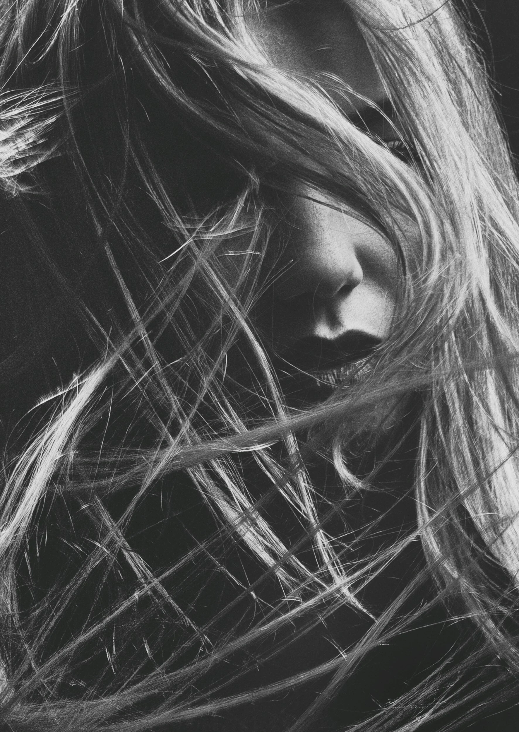 Black and white portrait of a woman with her hair covering part of her face, focused on her lips and nose.