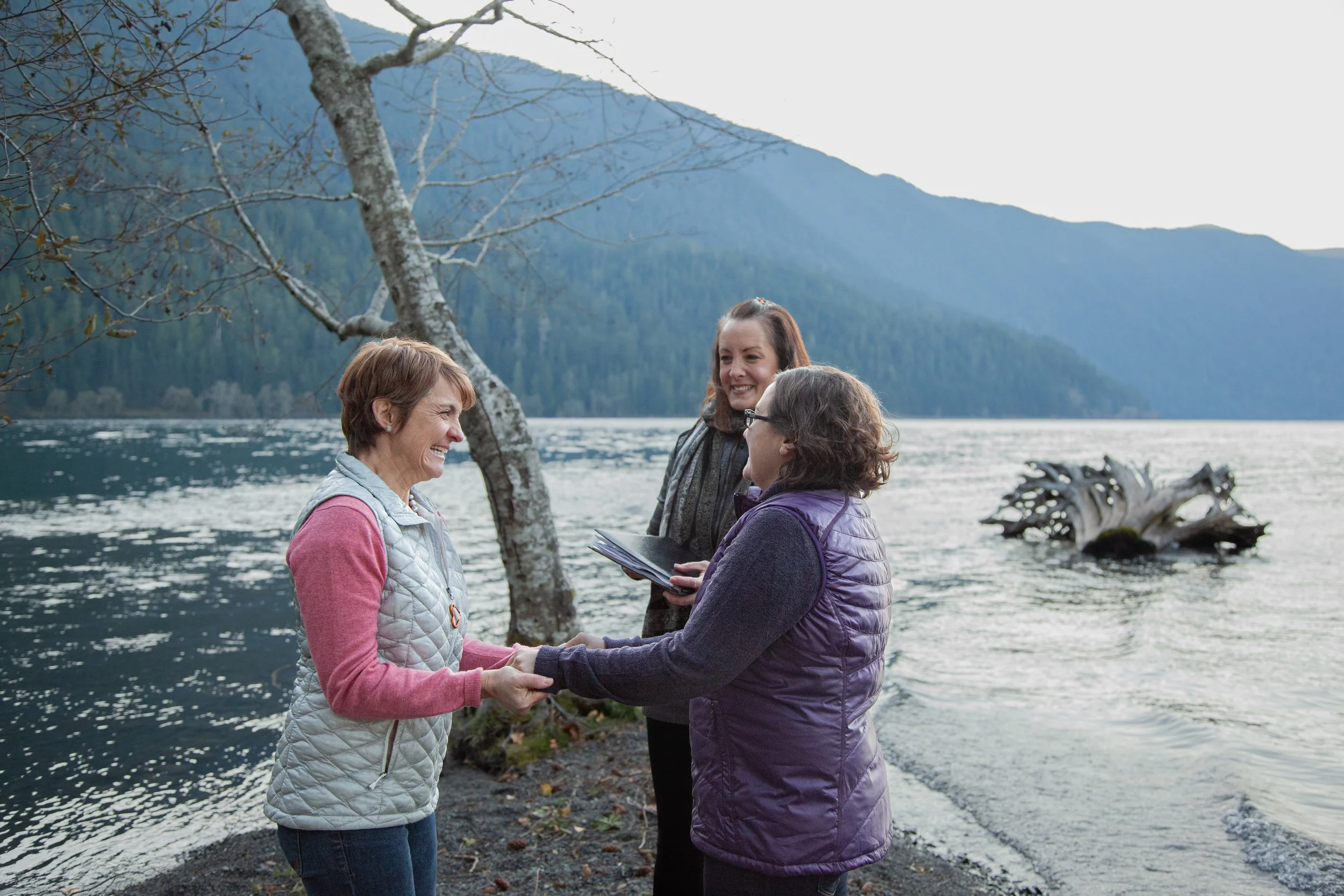 olympic peninsula, two brides embrace at the shore of lake crescent, elopement, ceremony, officiant,