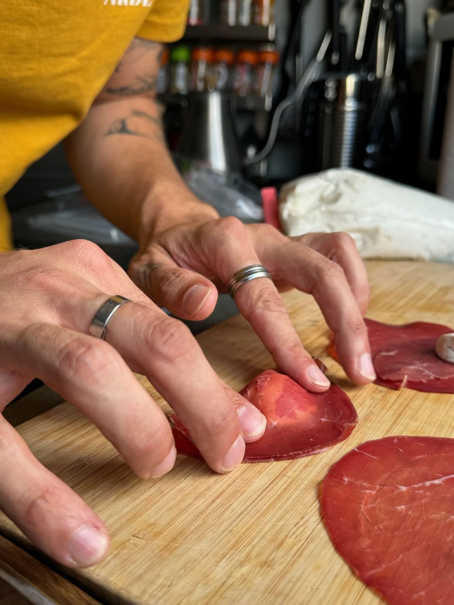 Une personne prépare de la viande sur une planche à découper, enroulant la viande avec ses mains.