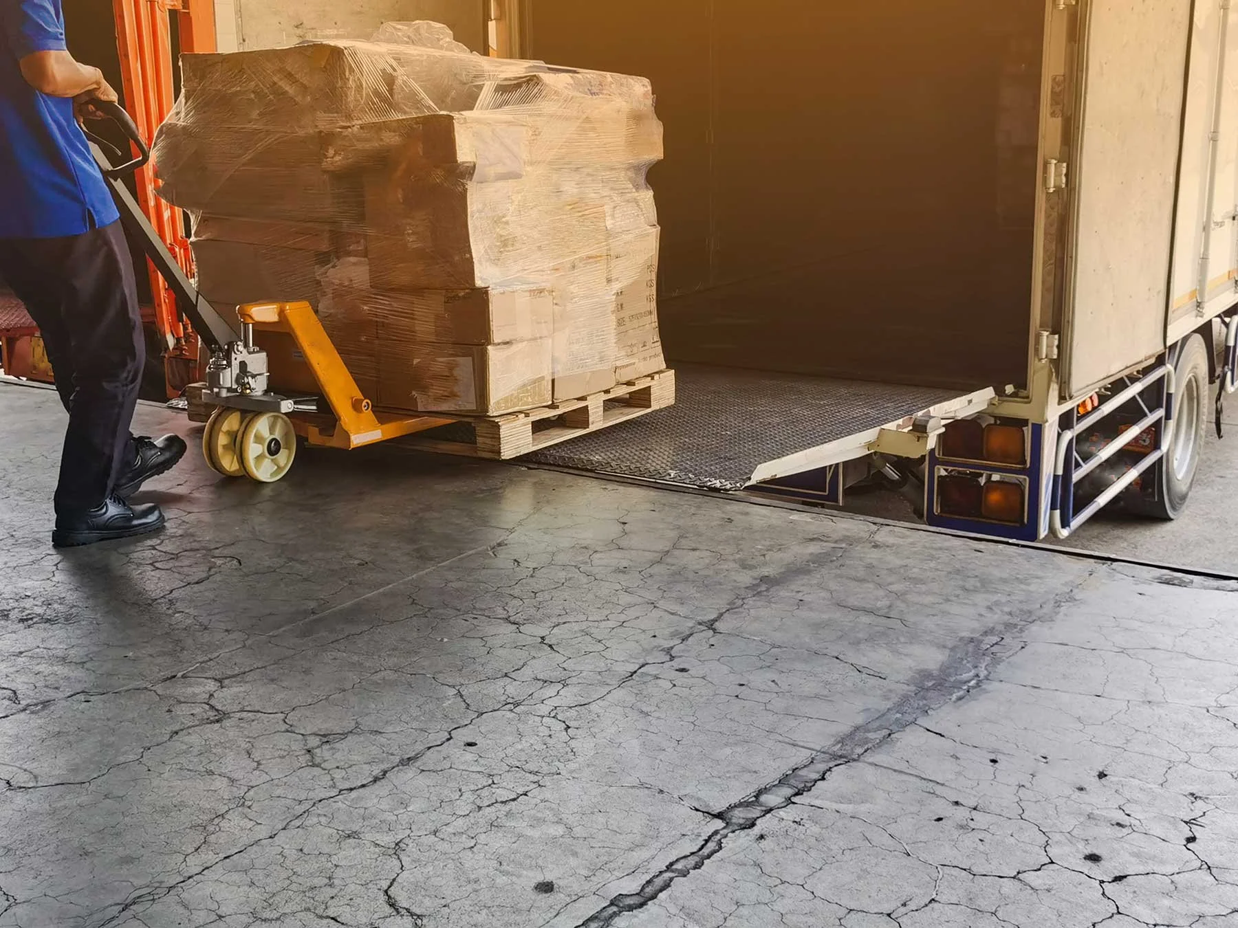 Worker unloading a stacked pallet off a shipping truck