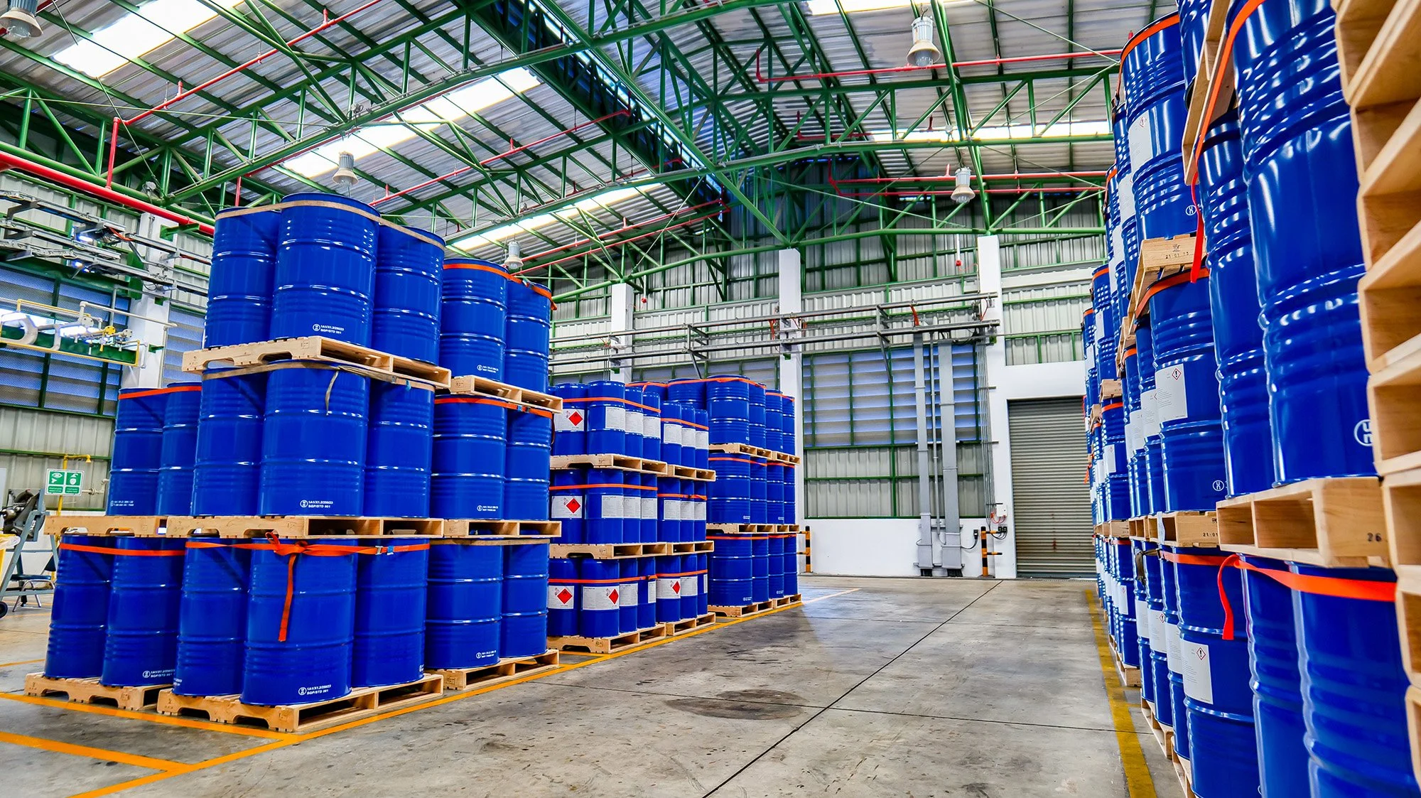 Blue chemical barrels stacked on wooden chemical pallets inside of a warehouse