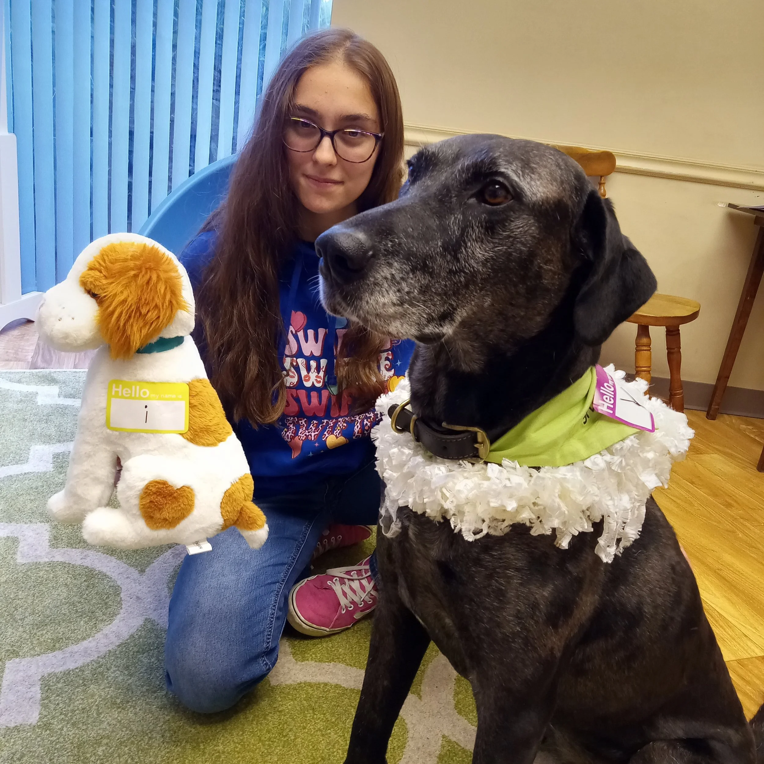 Speech therapy dog Delta and a stuffed animal representative of therapy dog Sky pose for a photo with animal-assisted reading therapy client.