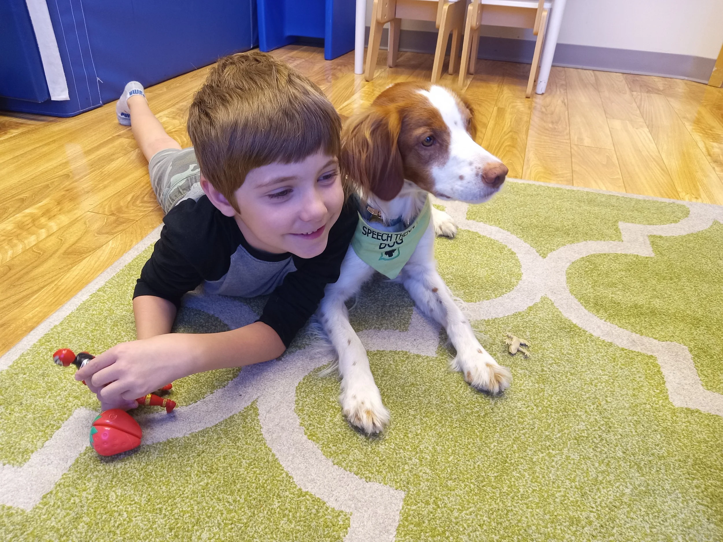 Speech therapy dog Sky snuggles with child in animal-assisted speech therapy (AAT).